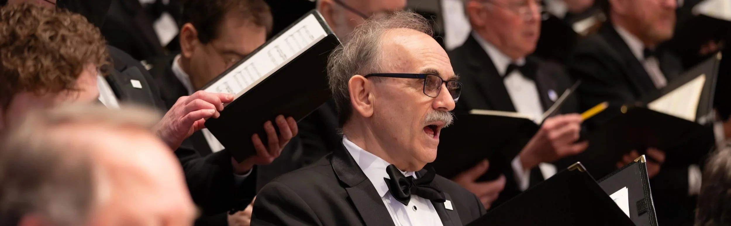 Close-up of chorus members singing.