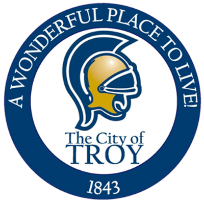 Logo of the City of Troy with a white background, featuring a stylized helmet and the text 'A Wonderful Place to Live! The City of Troy 1843'