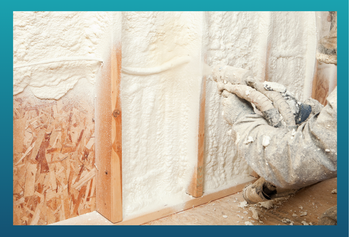 A worker applying spray foam insulation between wall studs in construction.