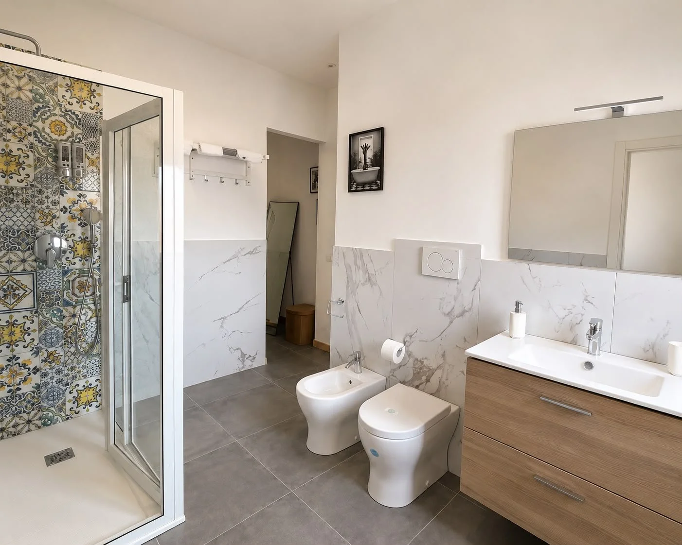 Bagno moderno con doccia, lavabo, toilette e bidet, pareti in marmo e piastrelle colorate nella doccia.