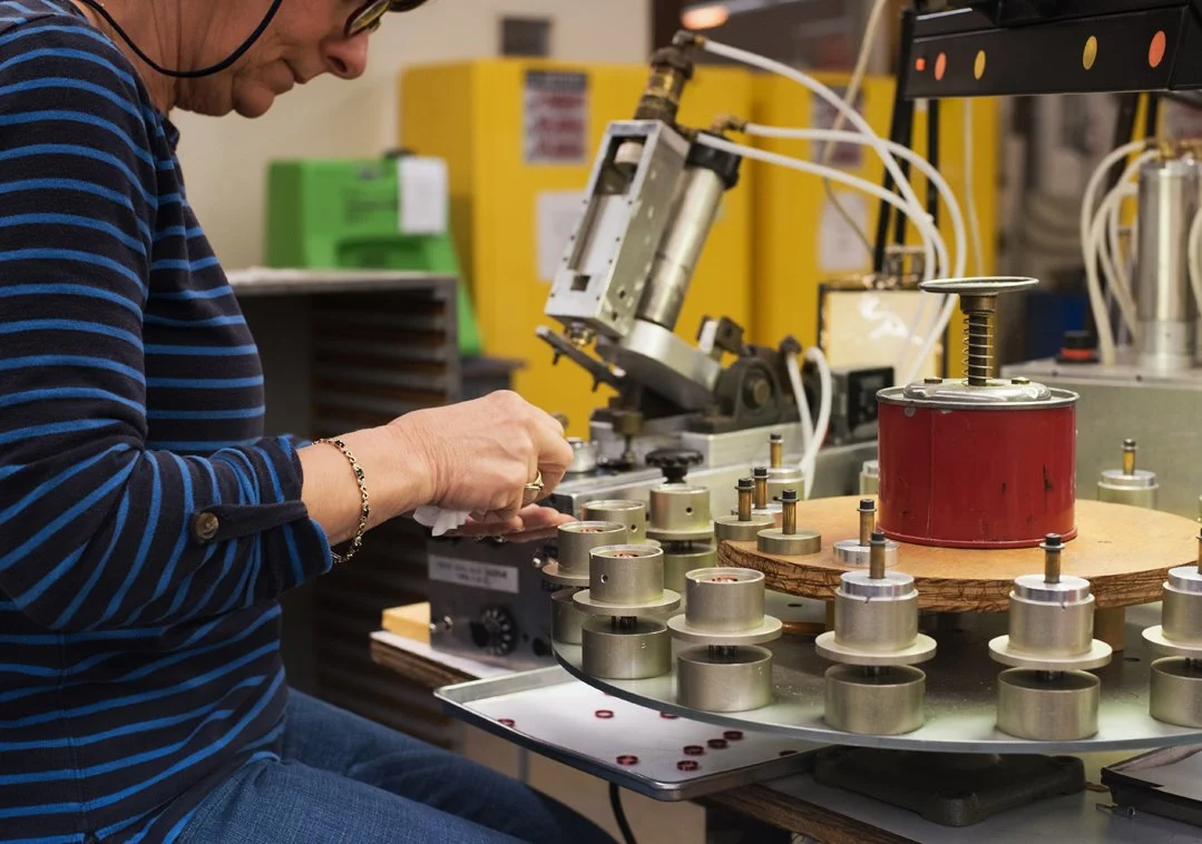 A person working with small components on the Koss Headphones production line.