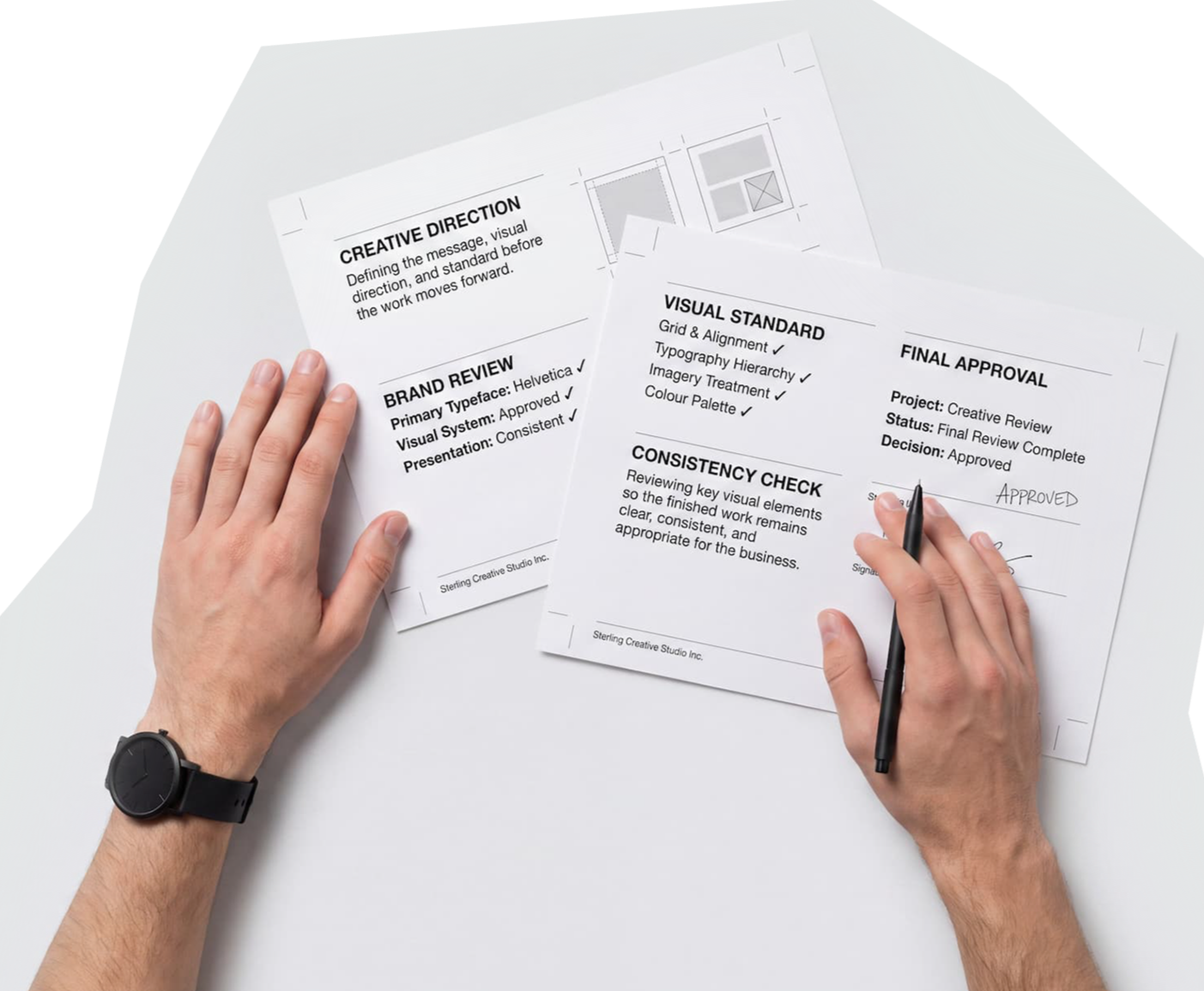 Hands reviewing printed creative direction and approval sheets.