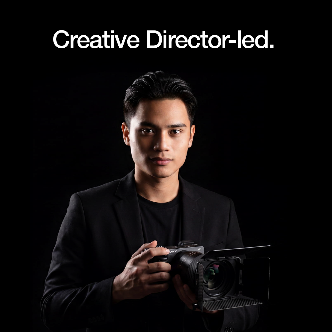 Man holding a cinema camera against a dark background.