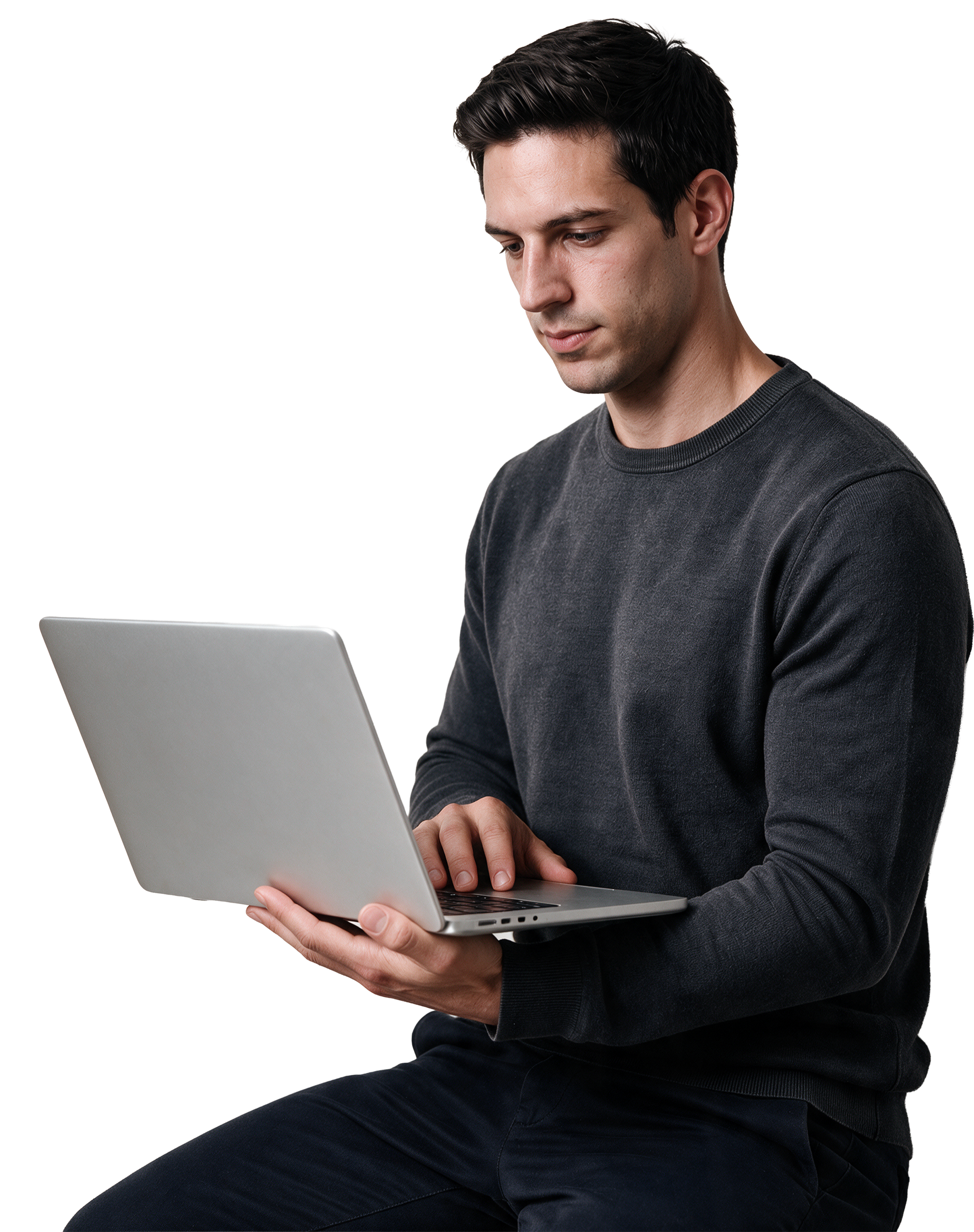 Young man with dark hair wearing a black sweatshirt, sitting and working on a laptop.