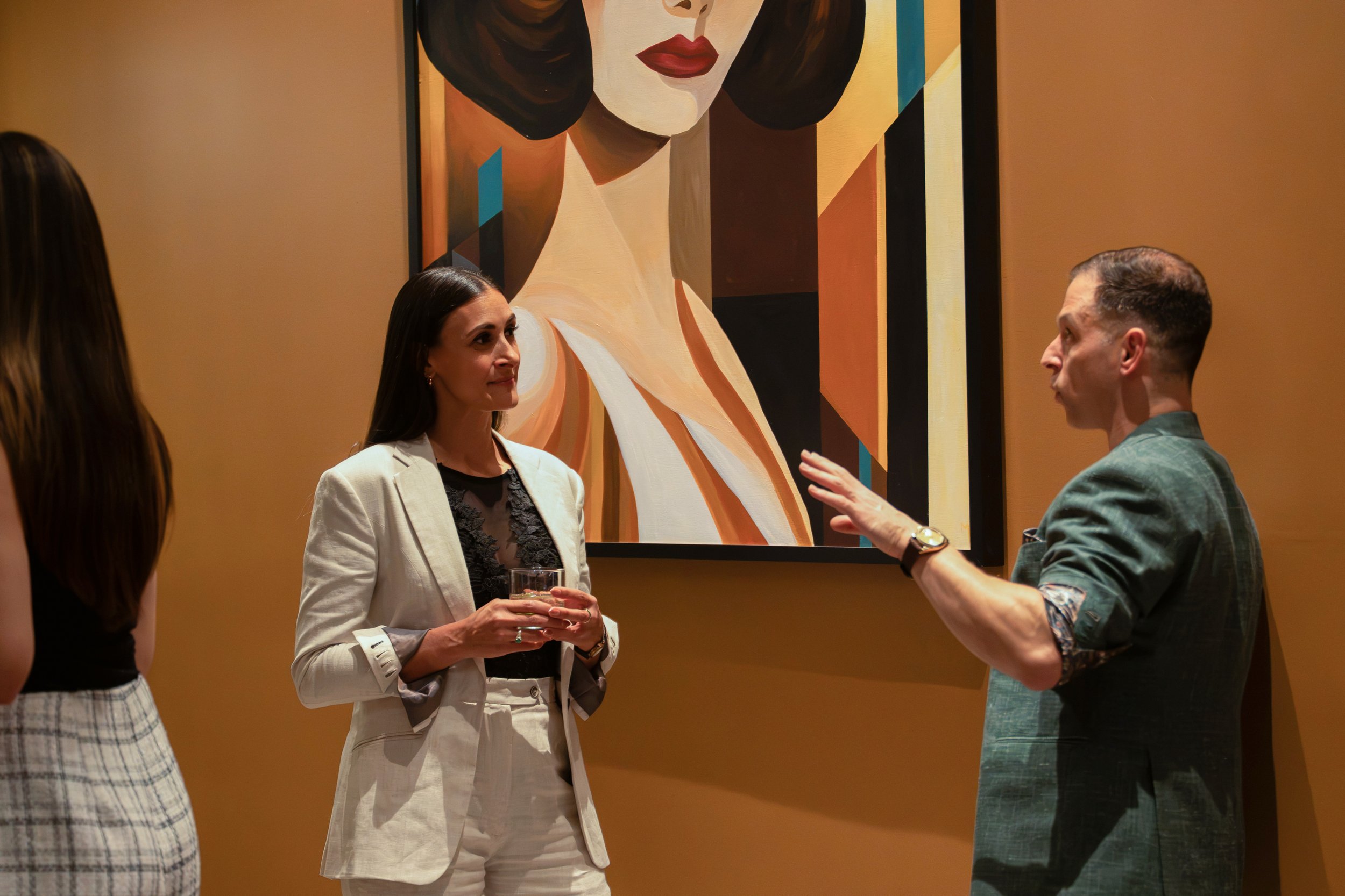 Guests networking during a private reception in The Annex beneath contemporary artwork and warm ambient lighting.