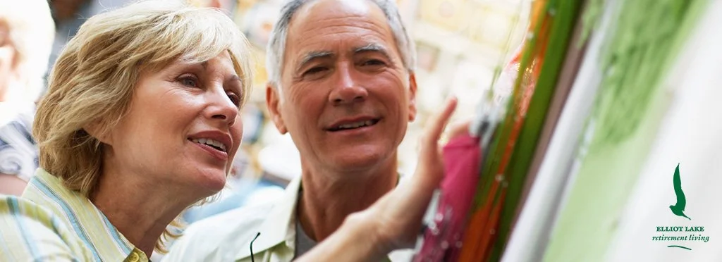 A couple shopping for paintings at an outdoor market.
