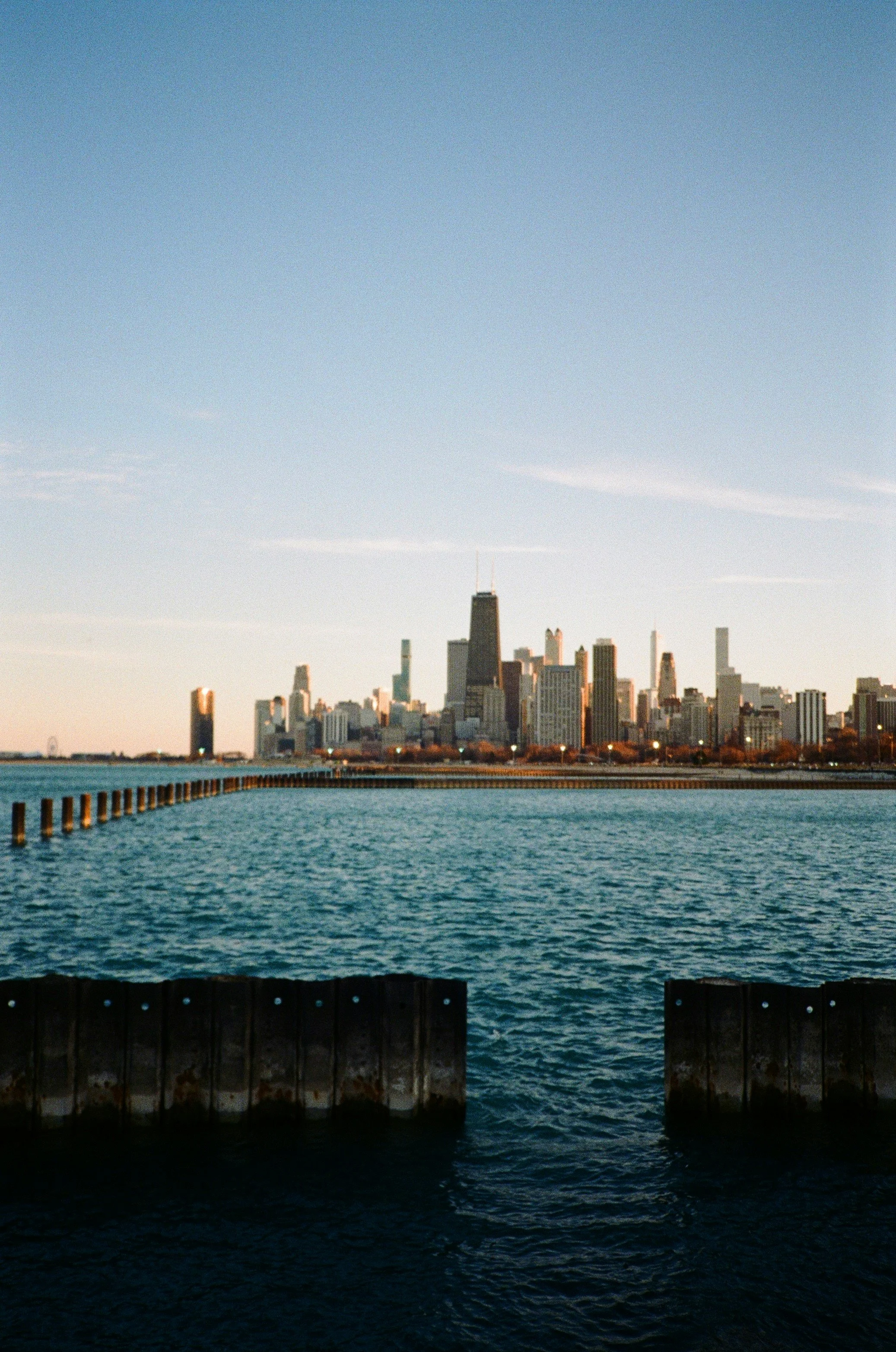 Chicago skyline with the John Hancock Center and Lake Michigan in the foreground during sunset.