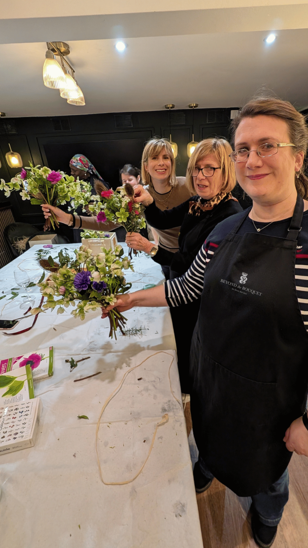 Several women assembling floral bouquets at a table.