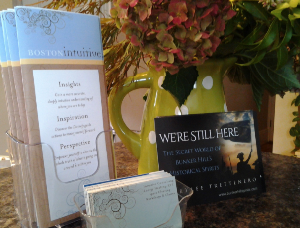 We’re Still Here: The Secret World of Bunker Hill’s Historical Spirits book and a floral arrangement on a table in a room.