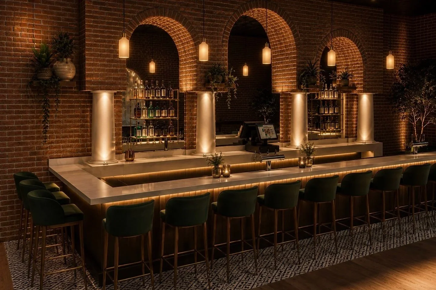 Upscale bar with a marble countertop, green bar stools, and a brick wall with arched niches illuminated by hanging pendant lights, displaying bottles of alcohol and potted plants.