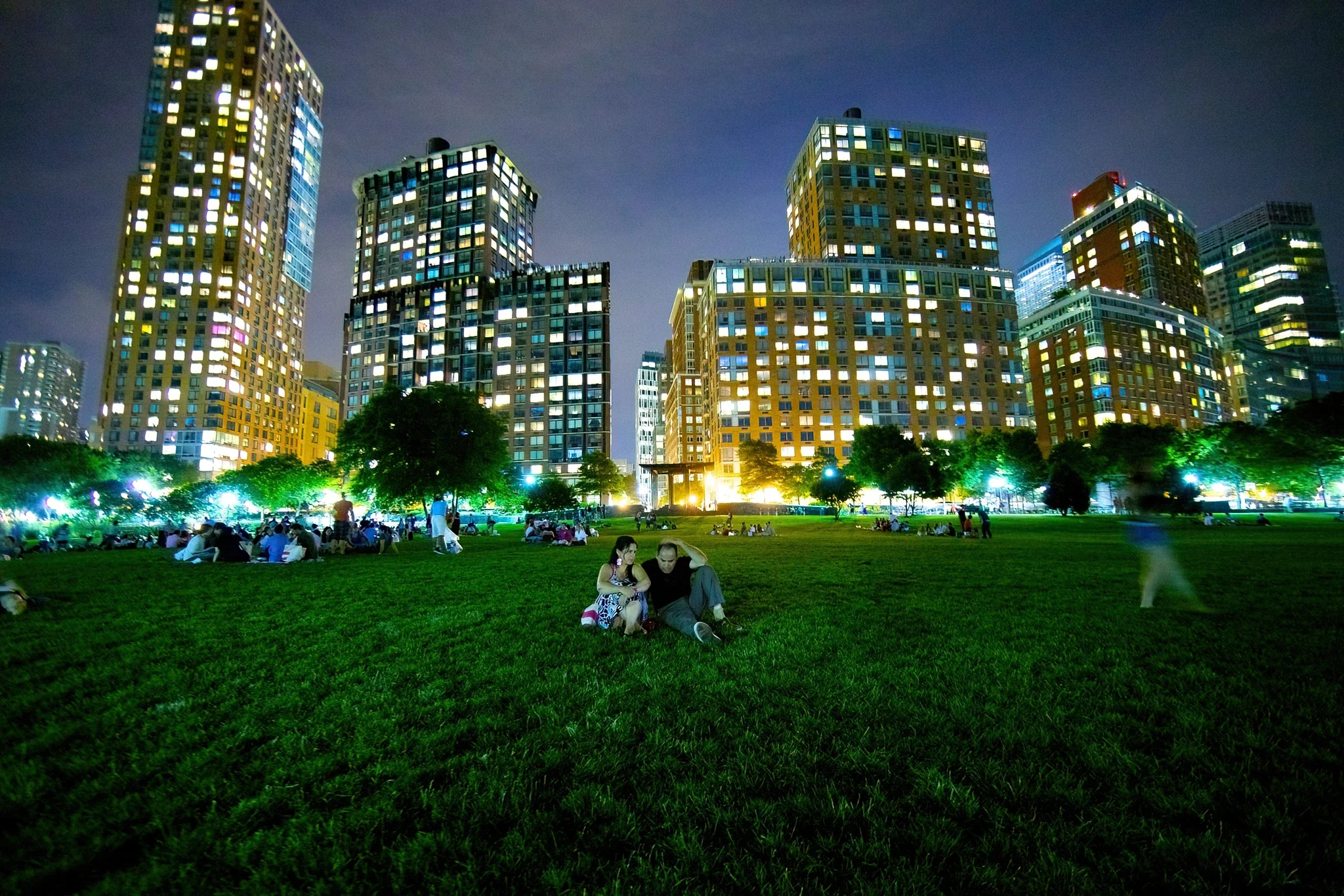 Couple sitting in grass — skyscrapers in background — Battery City Park, New York City — editorial portrait