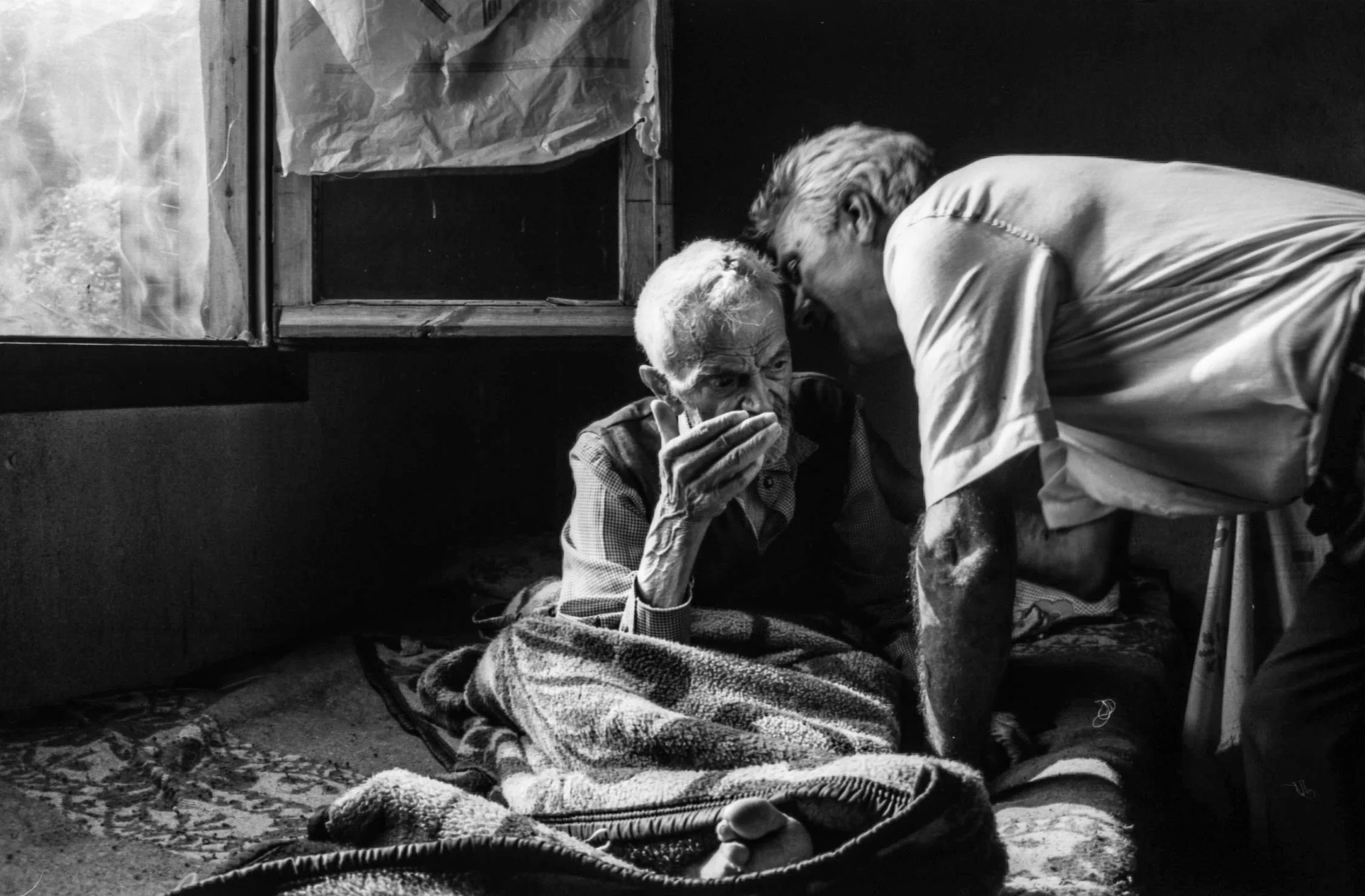 Son talking into his elderly deaf father's ear in rural Trikala, Greece — editorial 