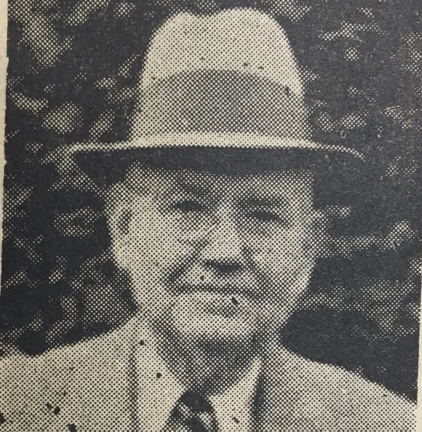 A black and white, pixelated portrait of a woman wearing a wide-brimmed hat.