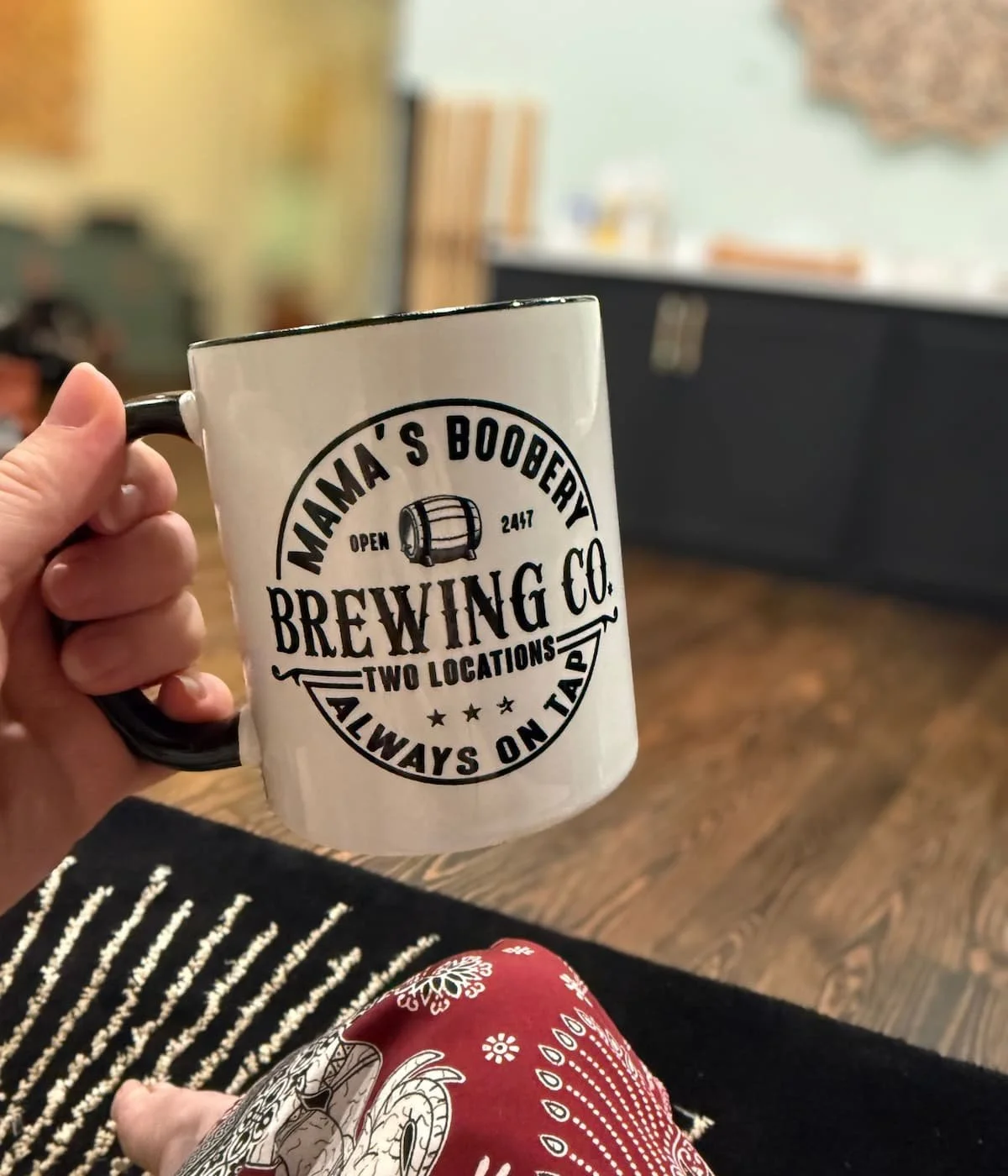 Doula, Hannah Servis, holding a coffee mug with the words "Mama's Boobery always on tap" on the front of the mug as she gets ready to provide breastfeeding support to her clients.