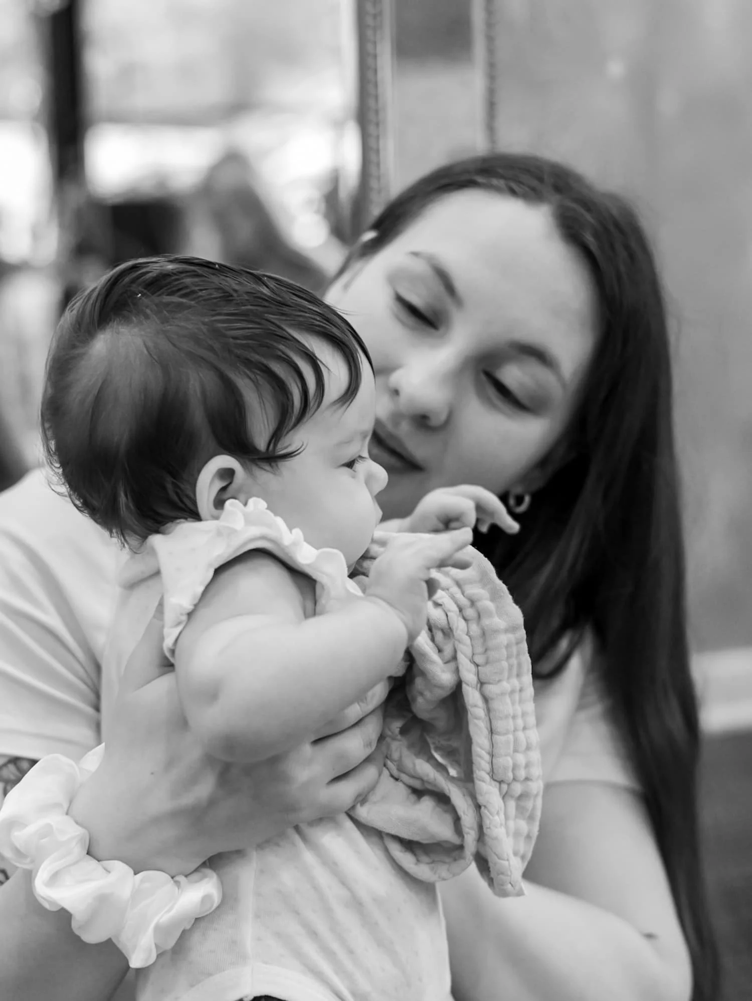 Postpartum doula, Hannah Servis, holding her newborn baby and smiling while she prepares to teach her clients about newborn care.
