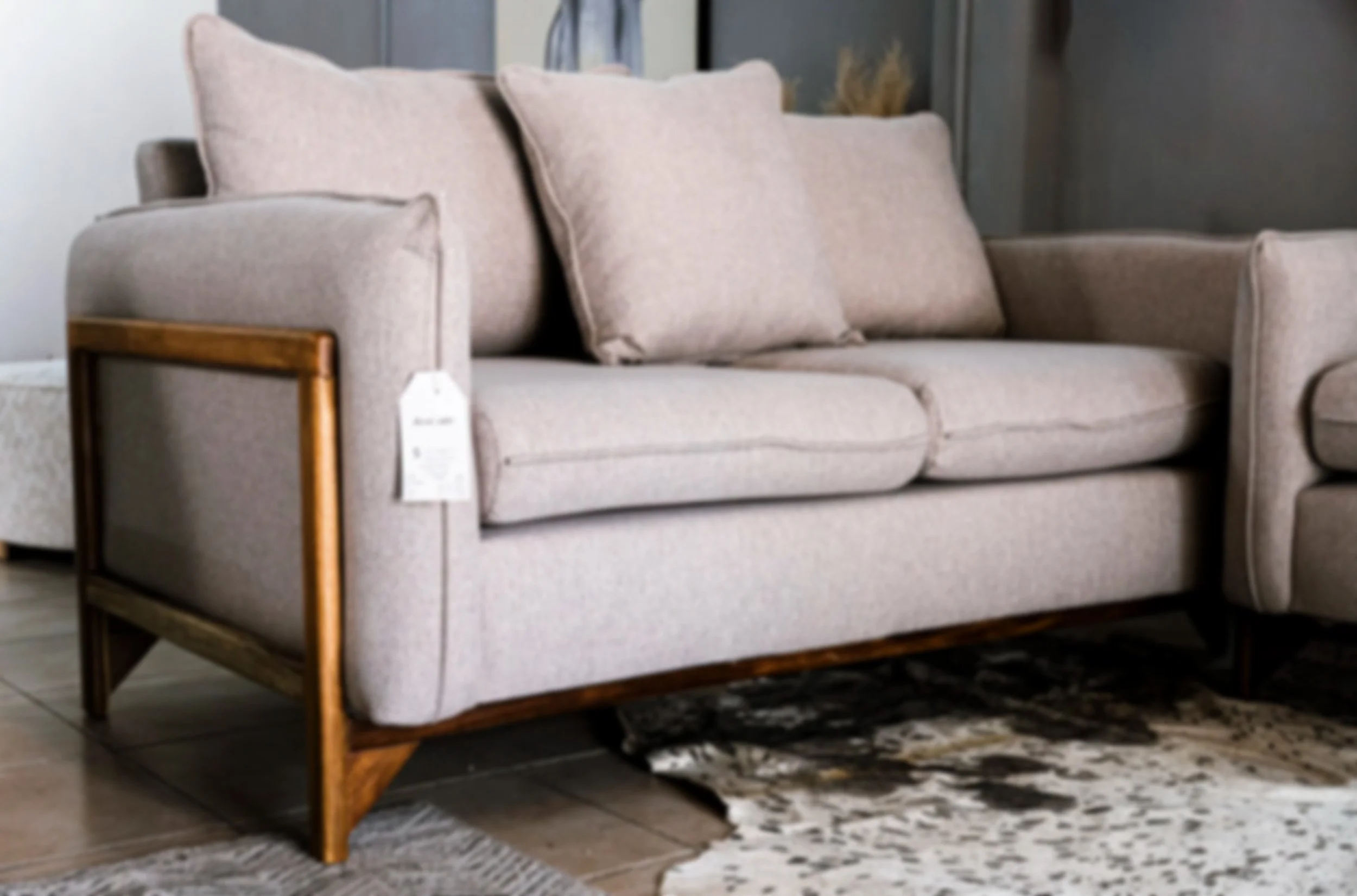 Sofá en tela beige con base de madera