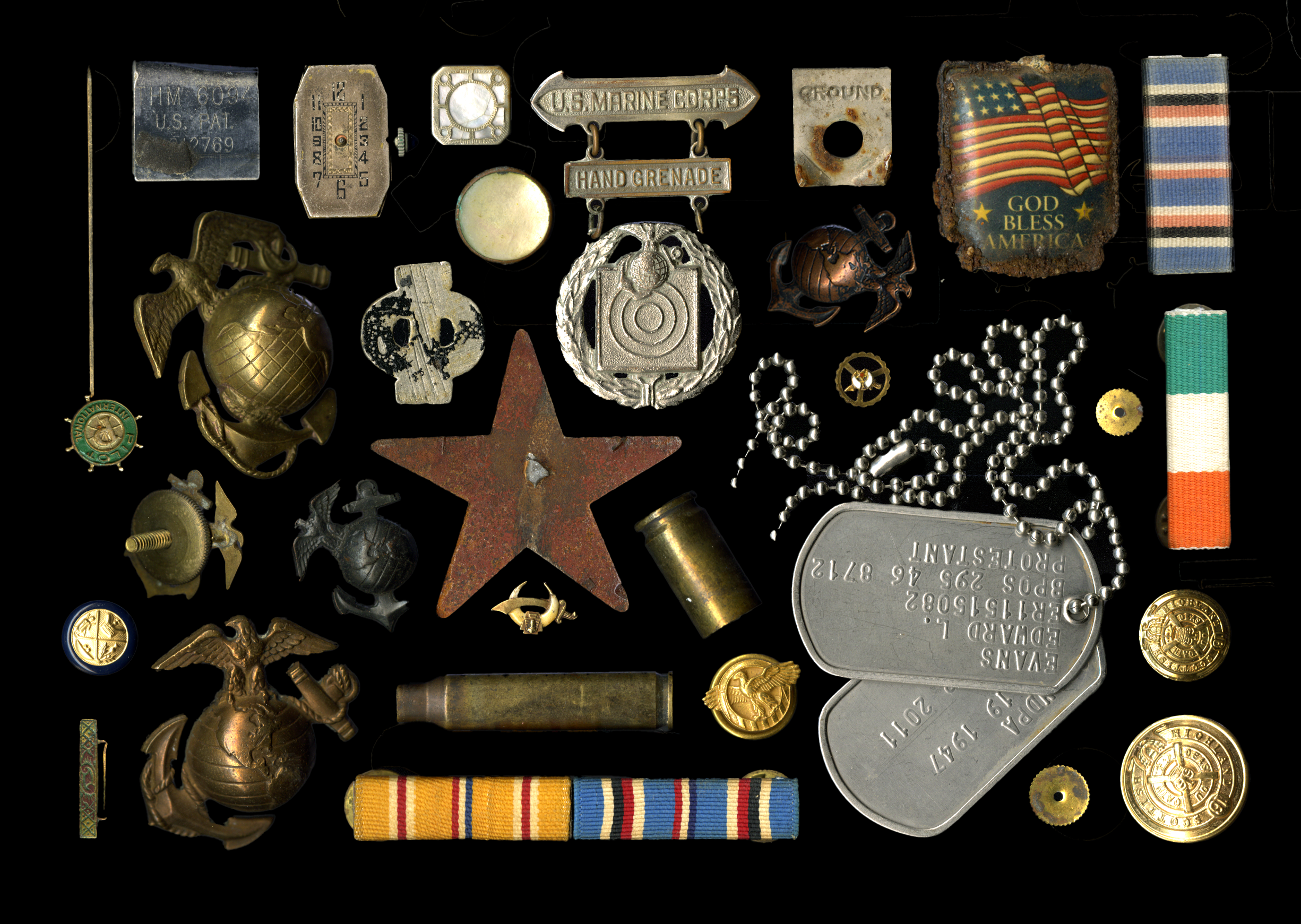 A collection of military and patriotic memorabilia, including medals, dog tags, ribbons, pins, and small items related to U.S. armed forces and American patriotism.