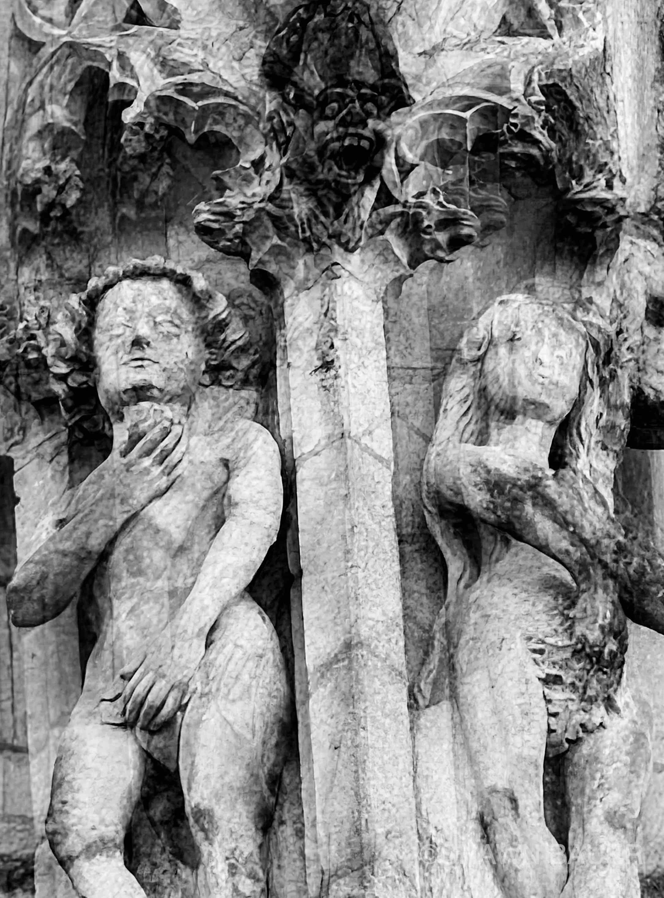 Black and white sculpture of four figures, with central figure holding a cross, surrounded by drapery and other figures.
