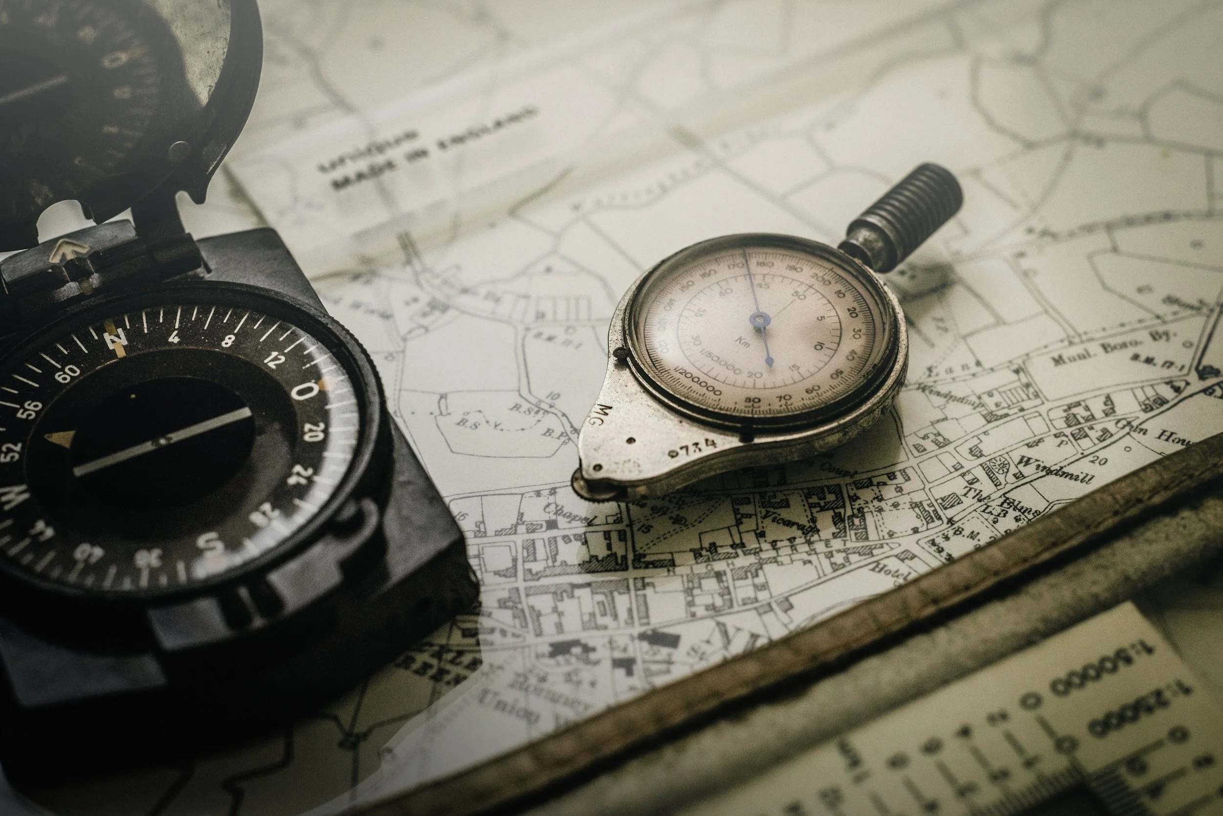 A map with a compass and a stopwatch on top, partially visible, suggesting navigation or planning.