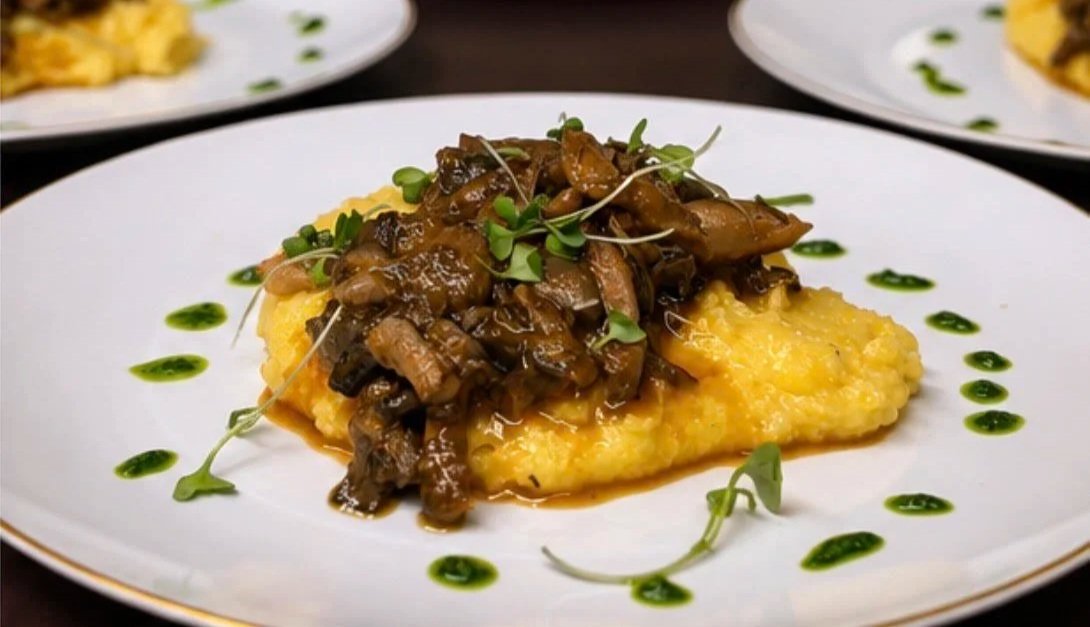 Creamy polenta topped with slow braised oyster mushrooms garnished with microgreens and a cilantro green sauce dots.