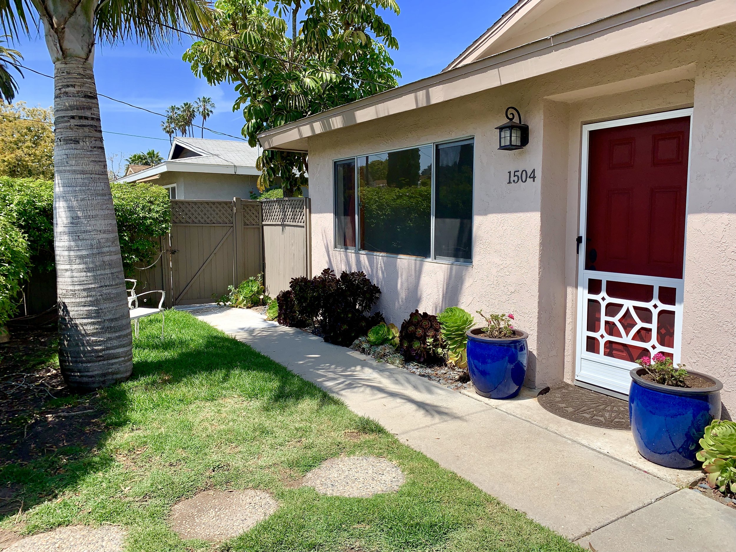 photo of the front of a single story home with a red door, and white screen door.