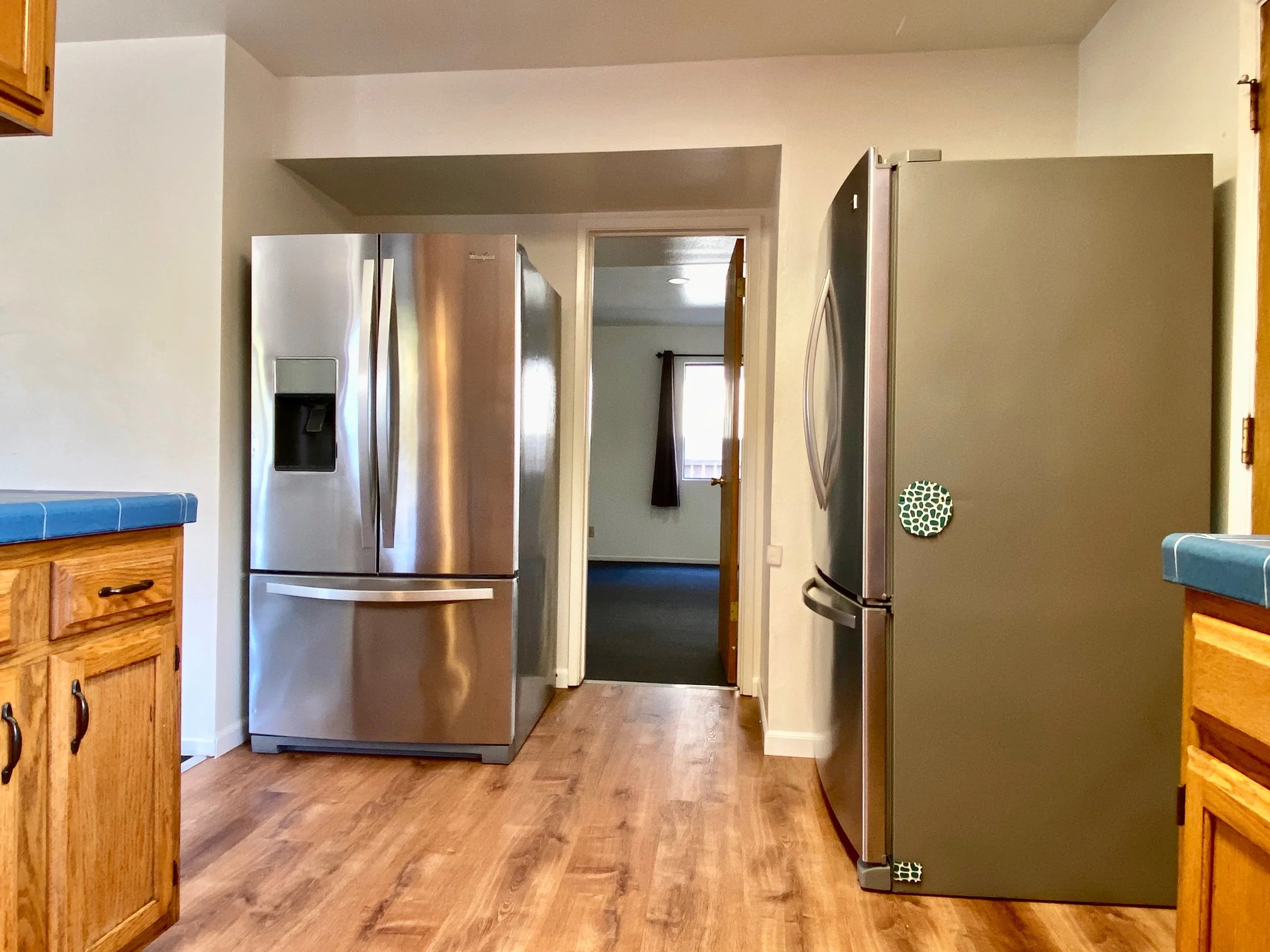 Kitchen with wooden cabinets, a stainless steel refrigerator, and a doorway leading to another room.