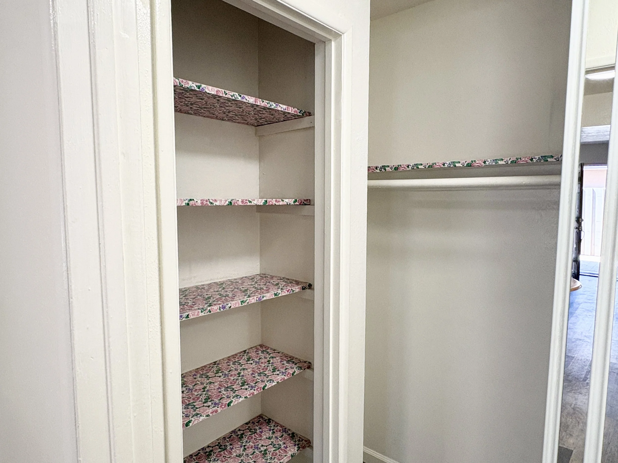 An empty closet with floral patterned shelves.