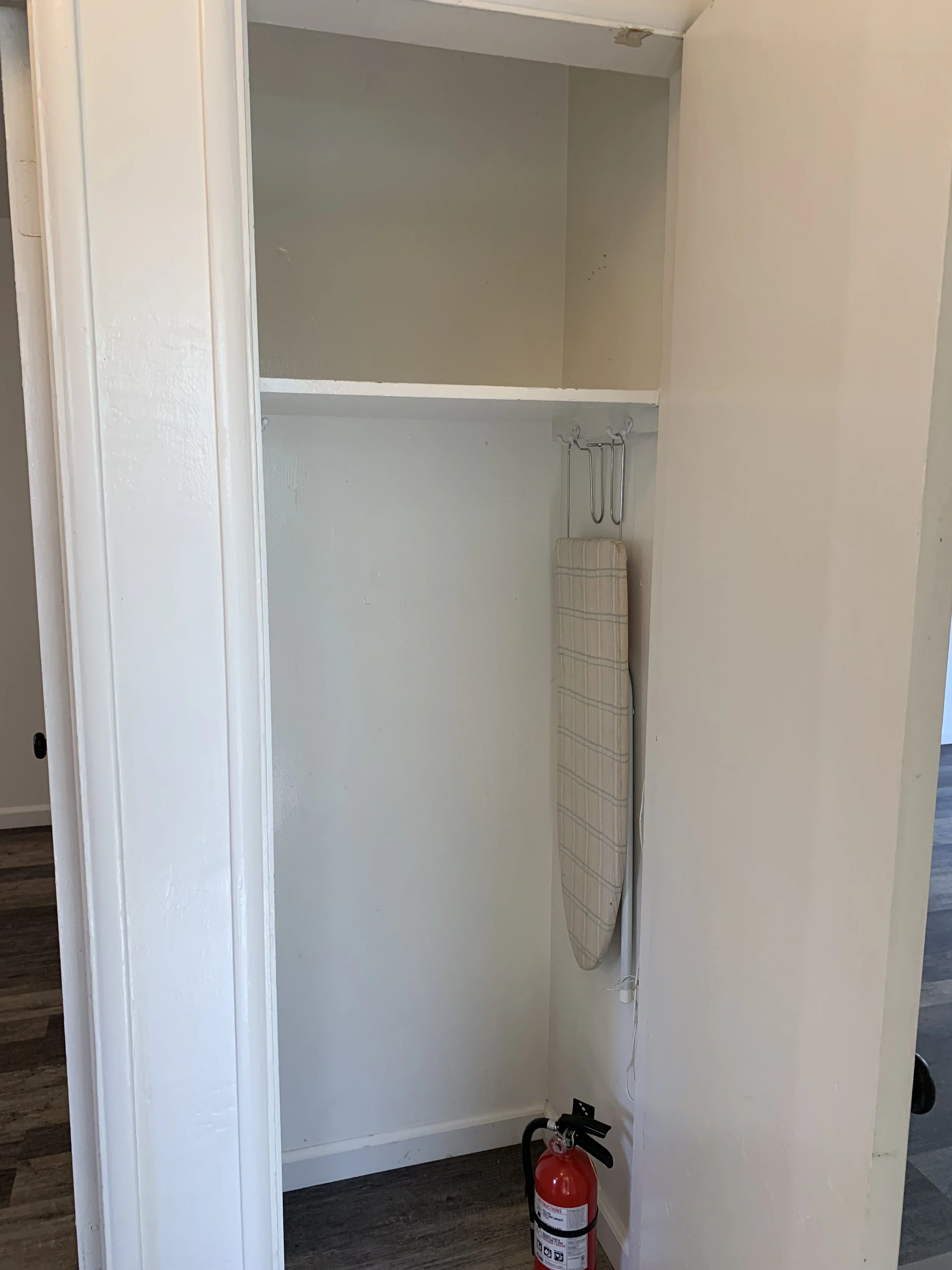 Empty hallway closet space with a fire extinguisher on the floor.