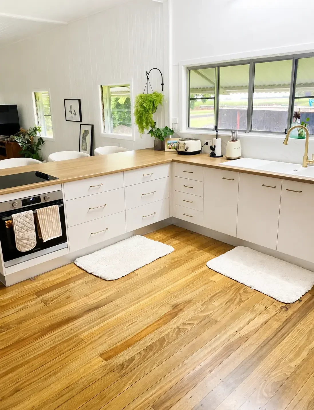 White custom kitchen cabinetry with timber benchtops, island bench and large windows.
