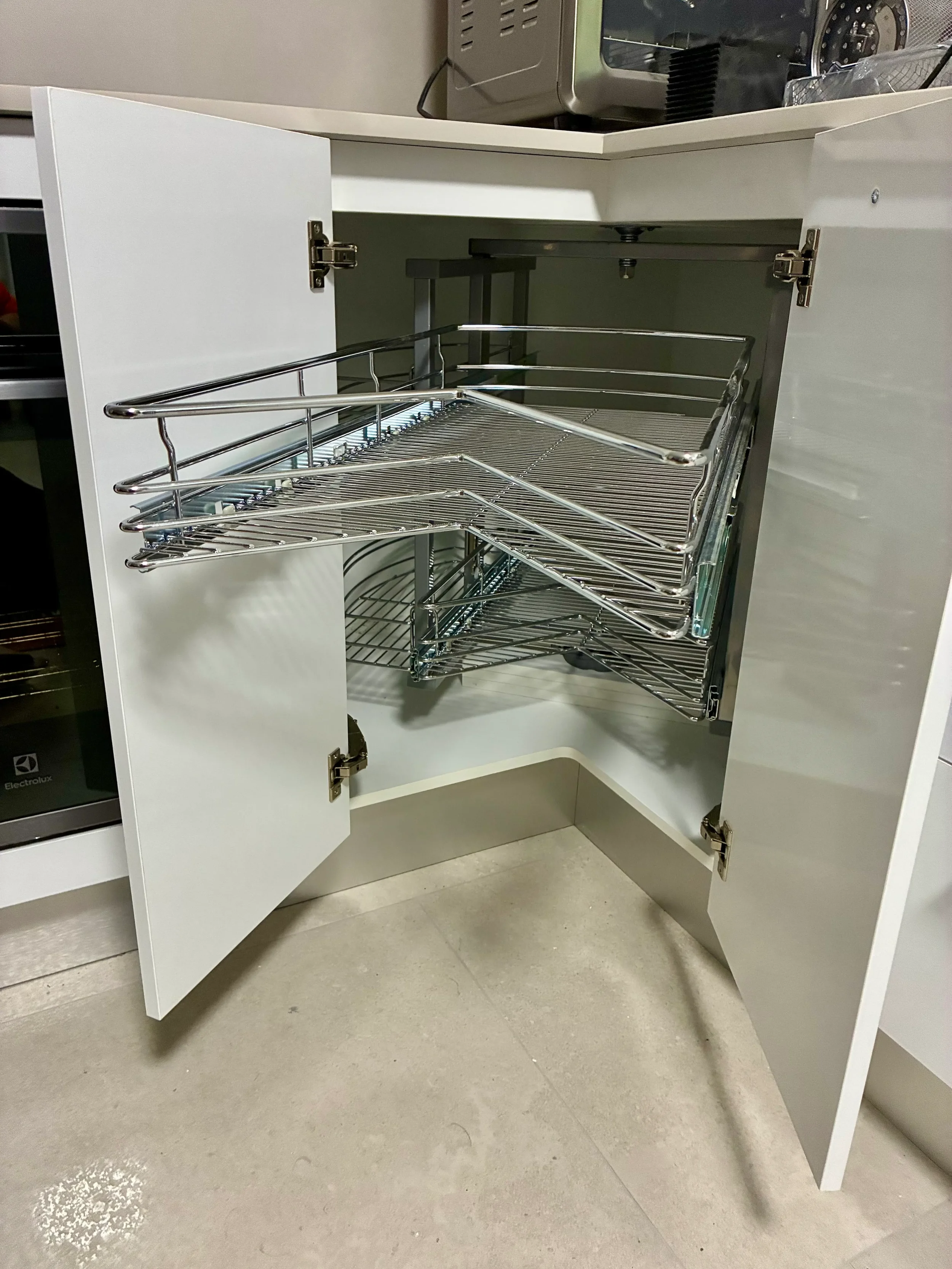 Open corner kitchen cabinet showing internal wire storage racks.
