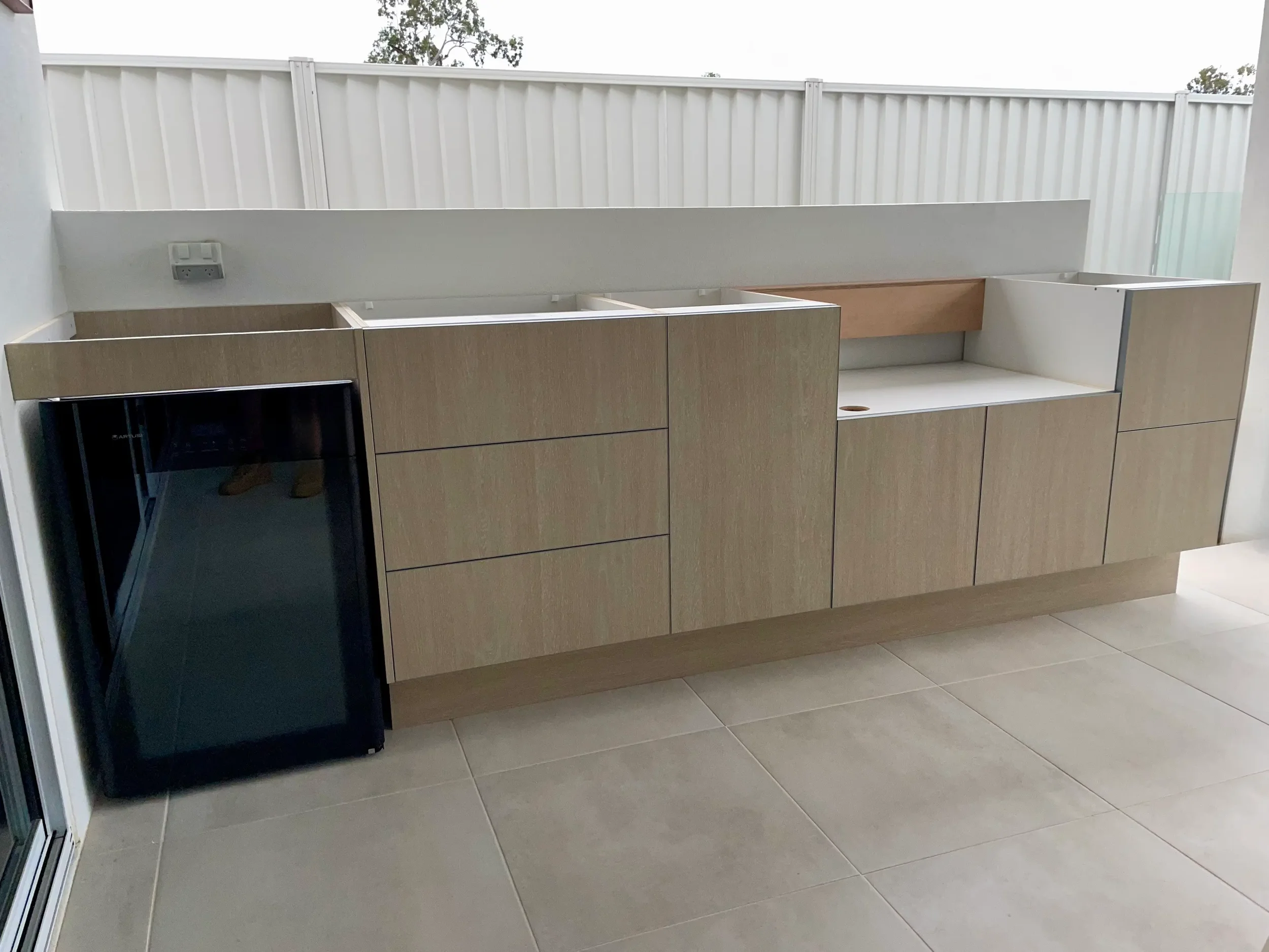 Light timber-look kitchen cabinetry with built-in microwave space and sink area.
