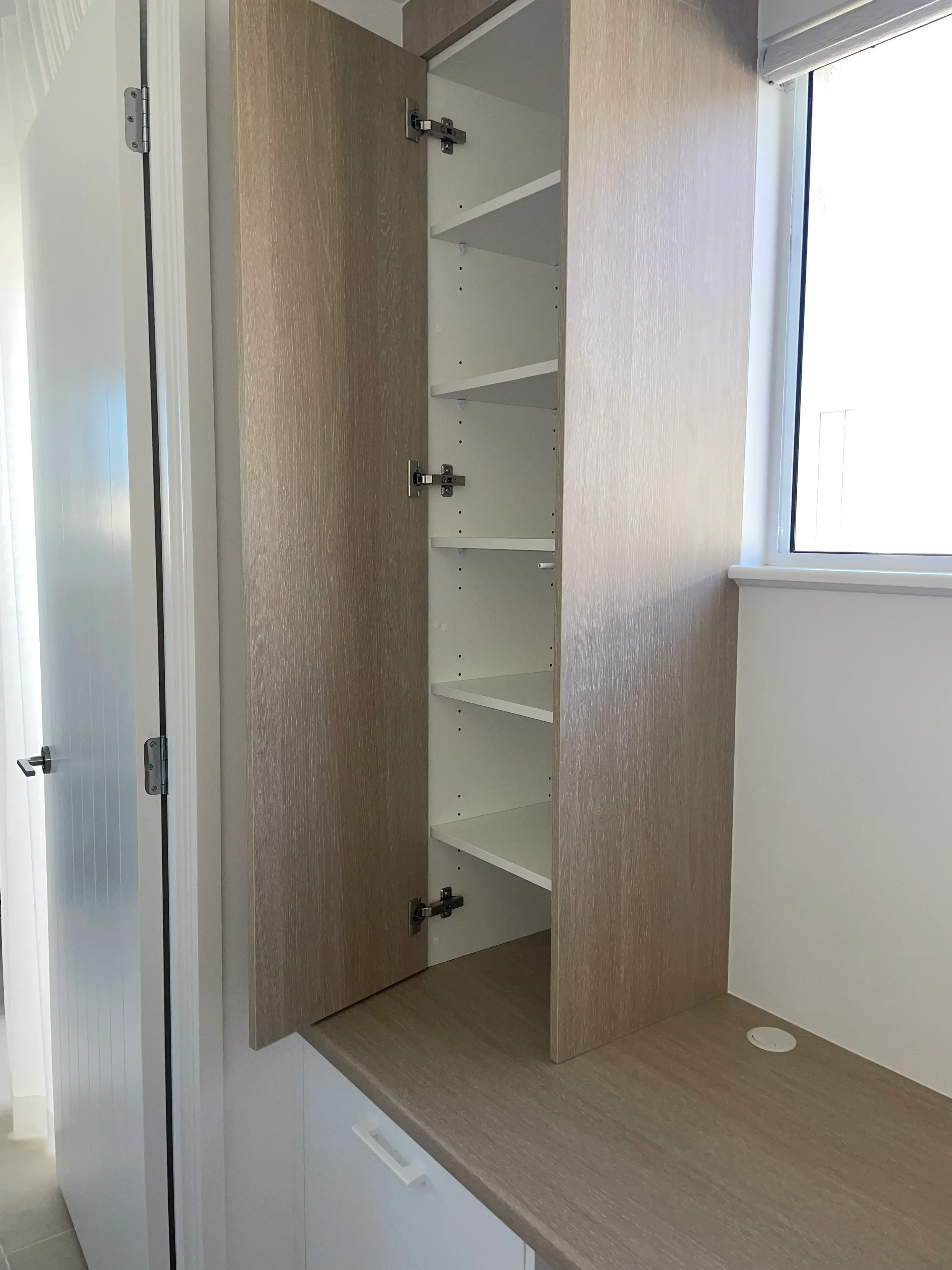 Open built-in cabinet showing internal shelving beside the window.
