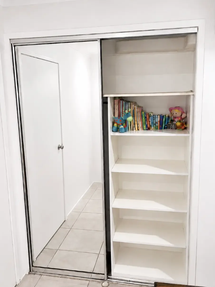 White built-in wardrobe with mirrored sliding door and internal shelving.
