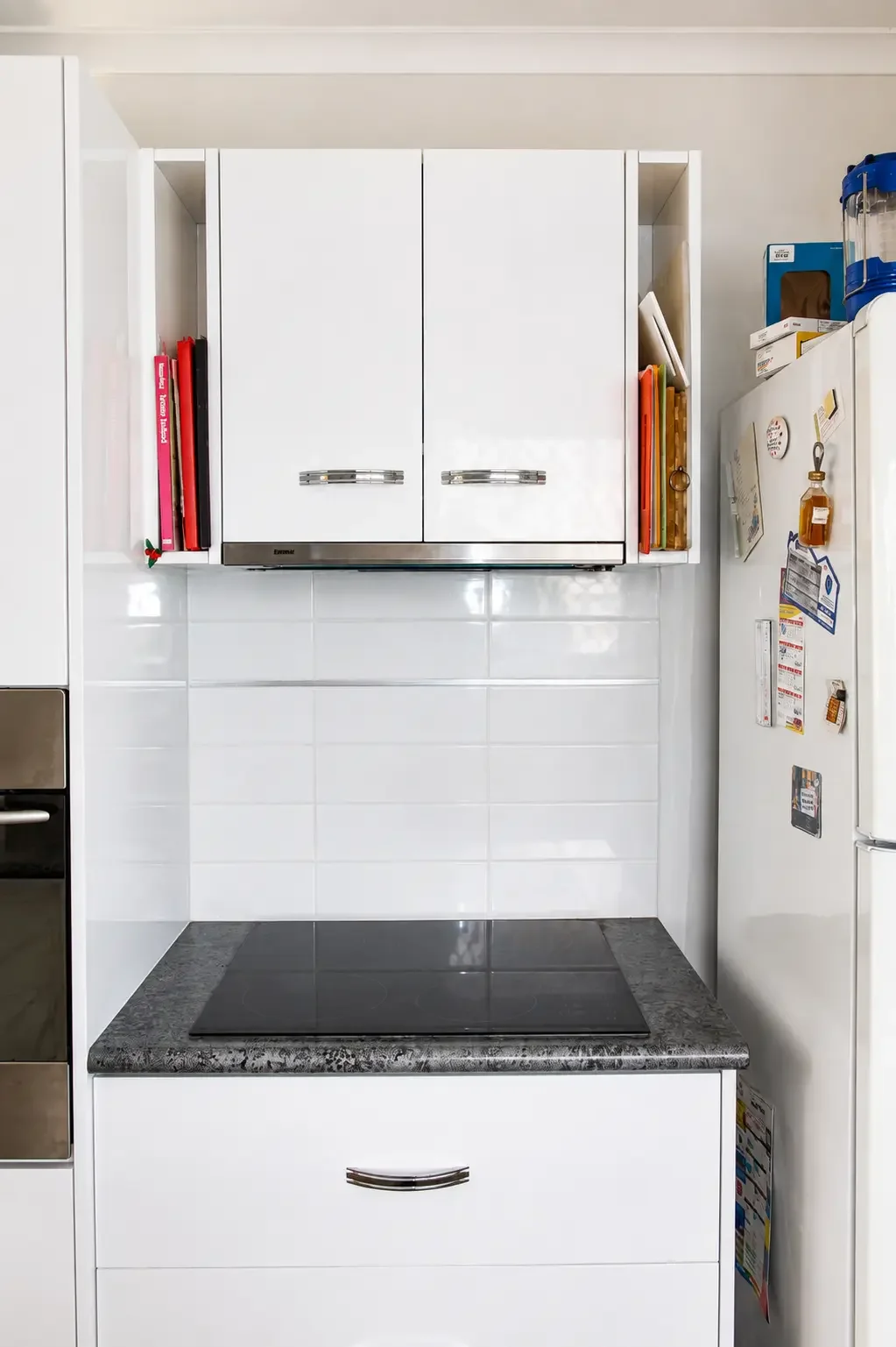 Compact white kitchen cabinetry with overhead storage and space for appliances.