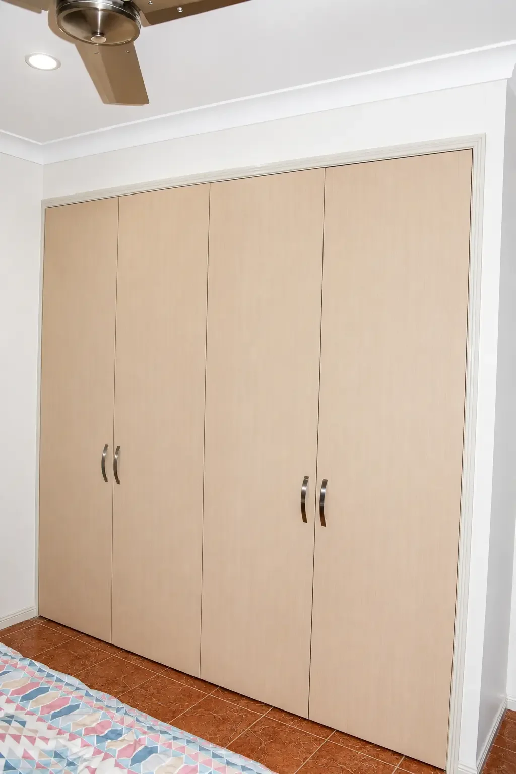 Four-door built-in wardrobe with light timber-look finish and metal handles.
