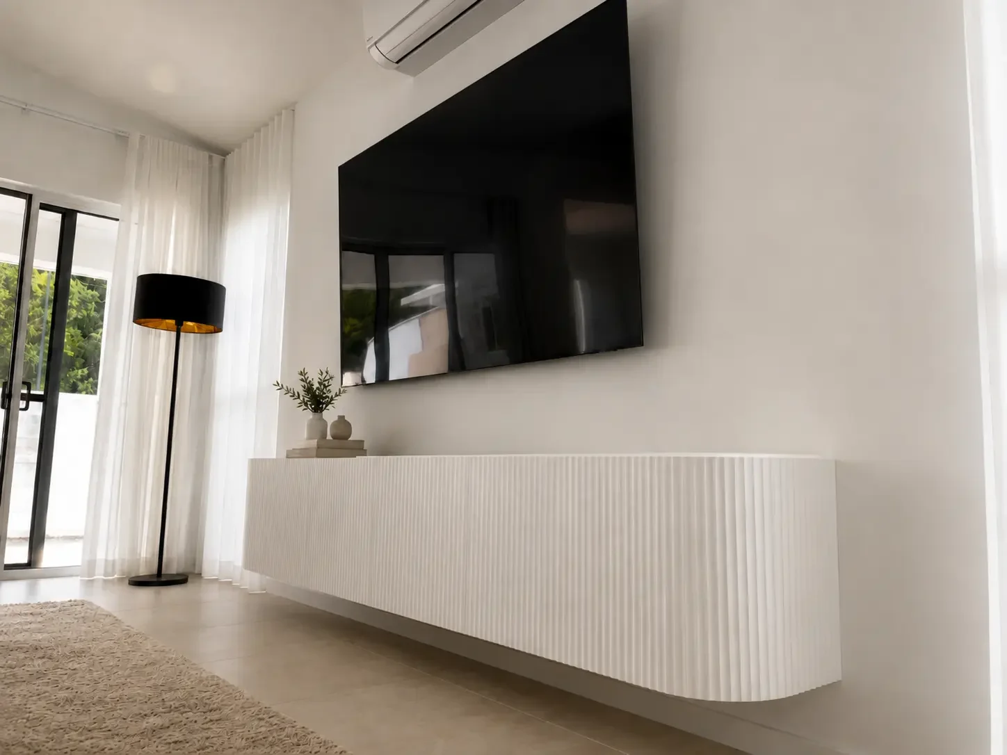 Wall-mounted white entertainment cabinetry beneath a flat-screen television.
