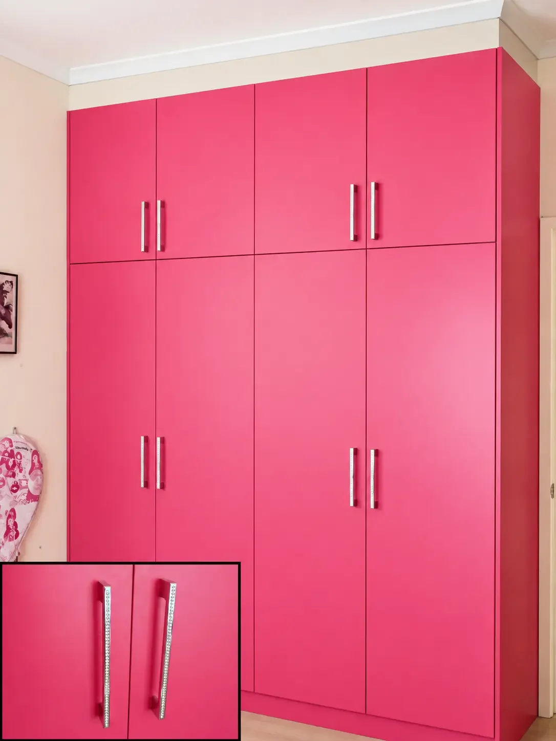 Pink built-in wardrobe cabinetry with silver handles and matching lower drawers.
