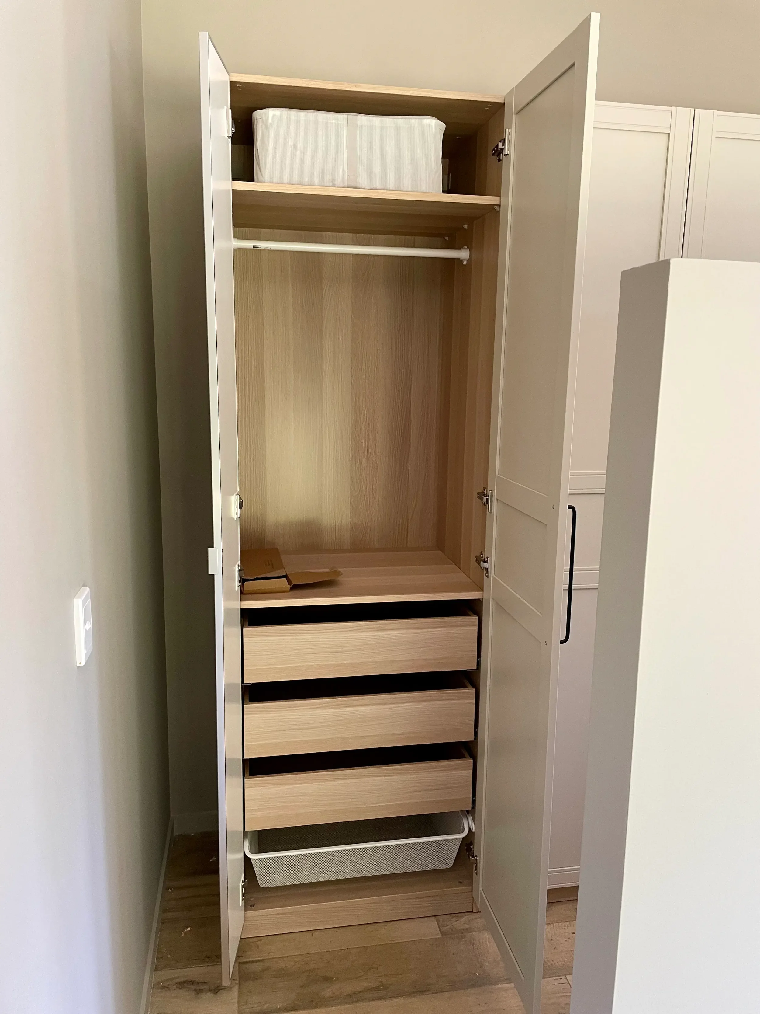 Open white built-in wardrobe with hanging space, shelving and internal drawers.
