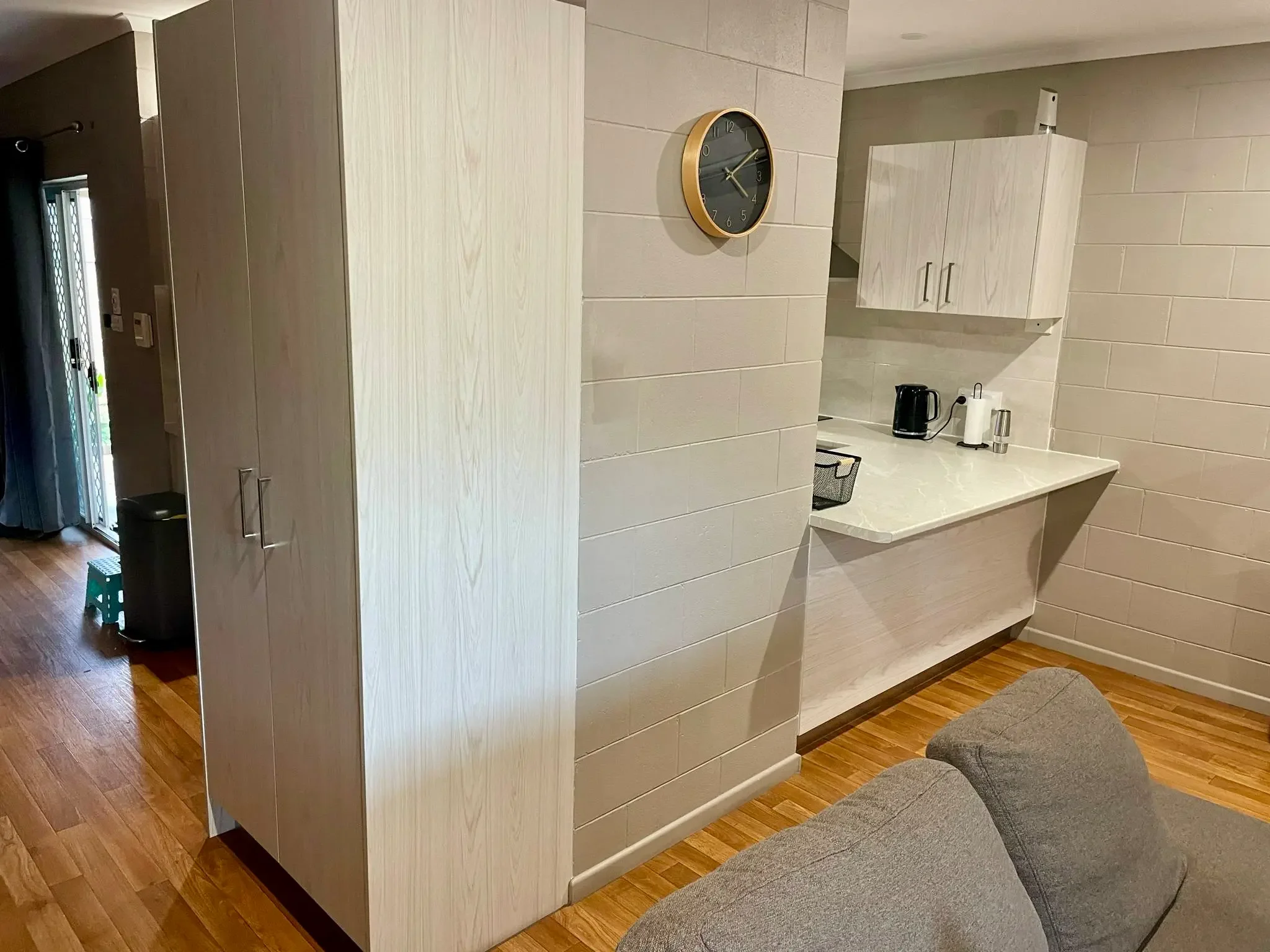Compact kitchen cabinetry with open shelving, bench space and timber flooring.
