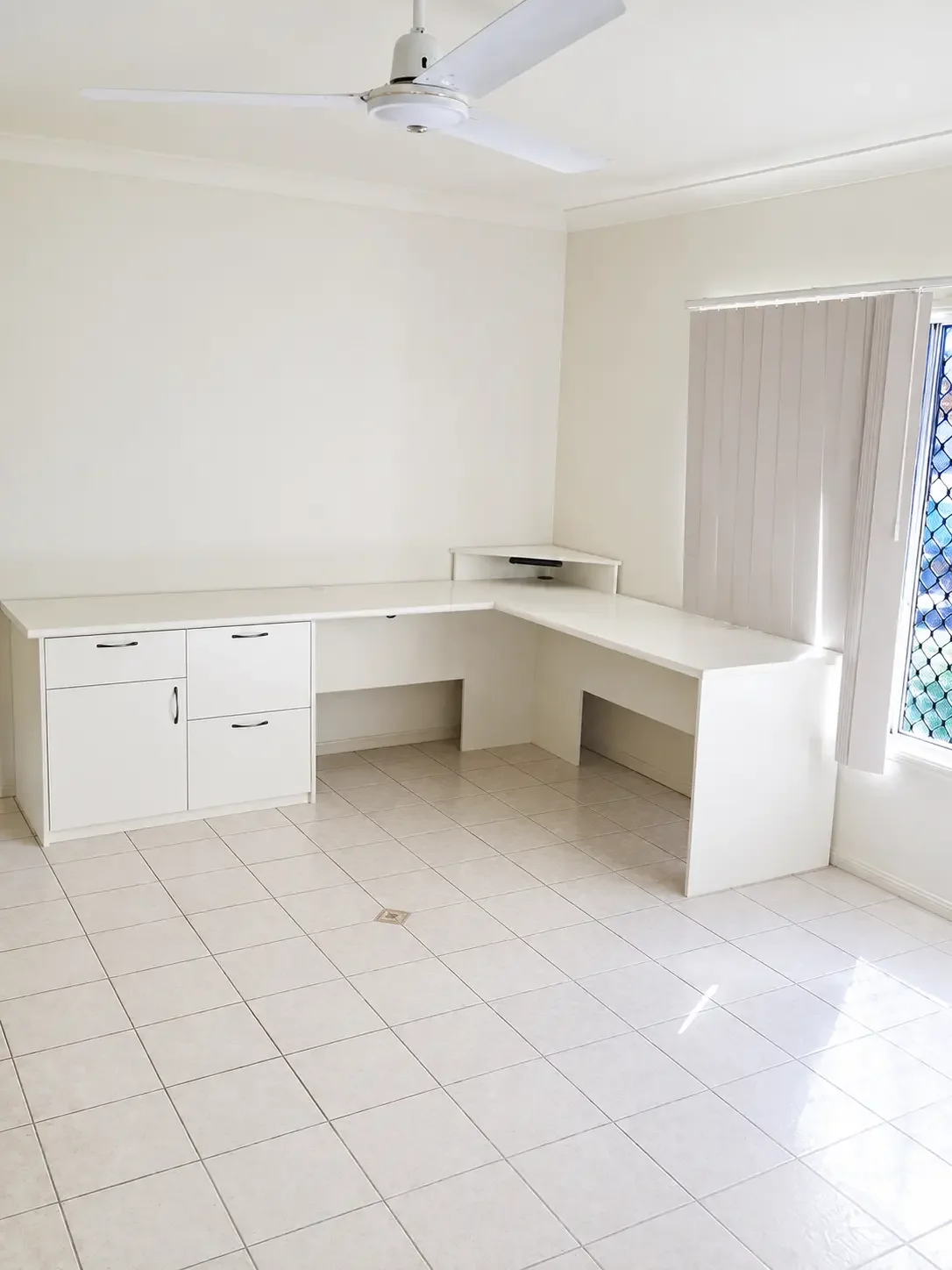 White built-in study desk with overhead cabinetry and storage beside the window.
