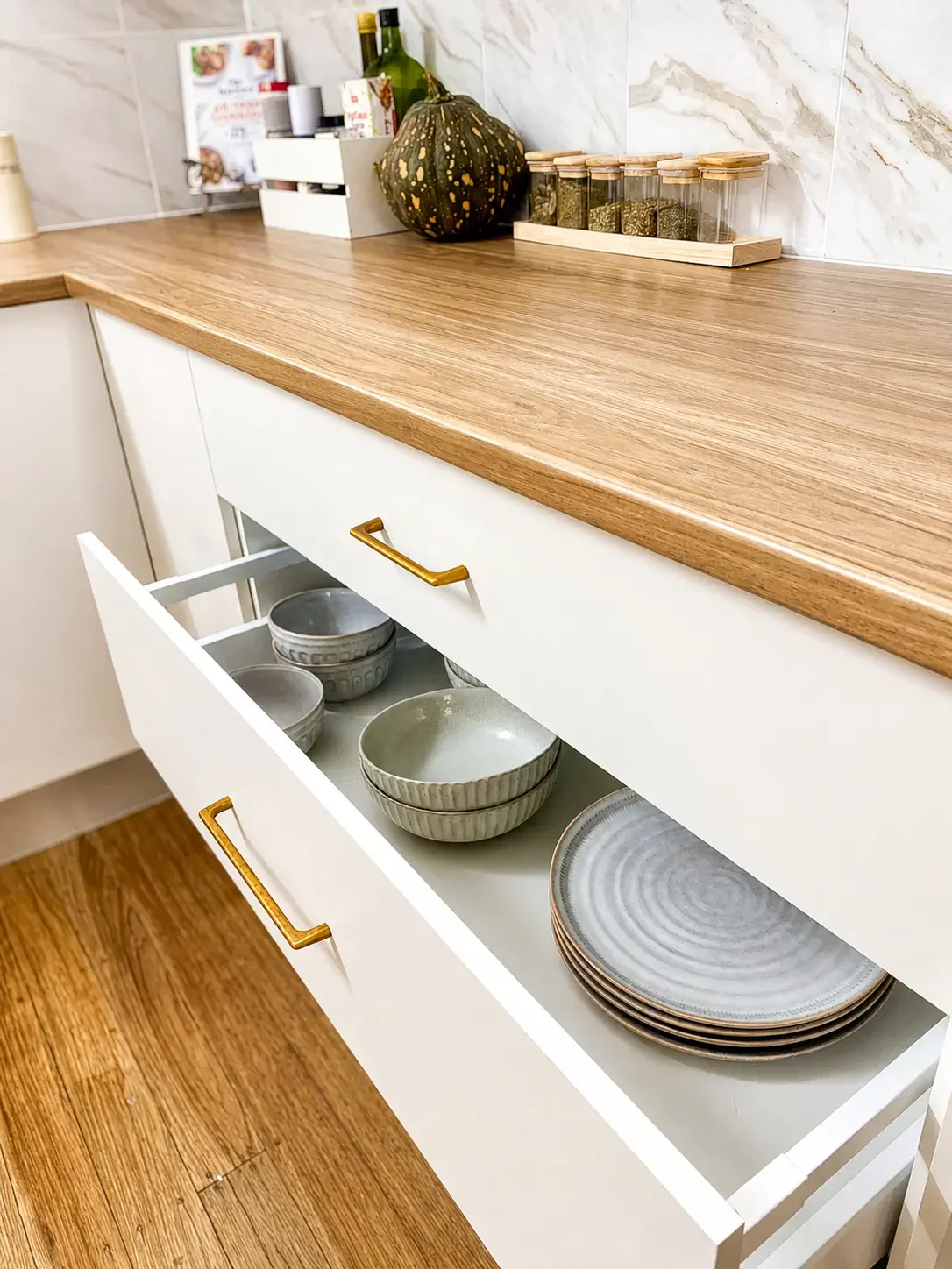 Open kitchen drawers showing custom internal storage beneath a timber benchtop.
