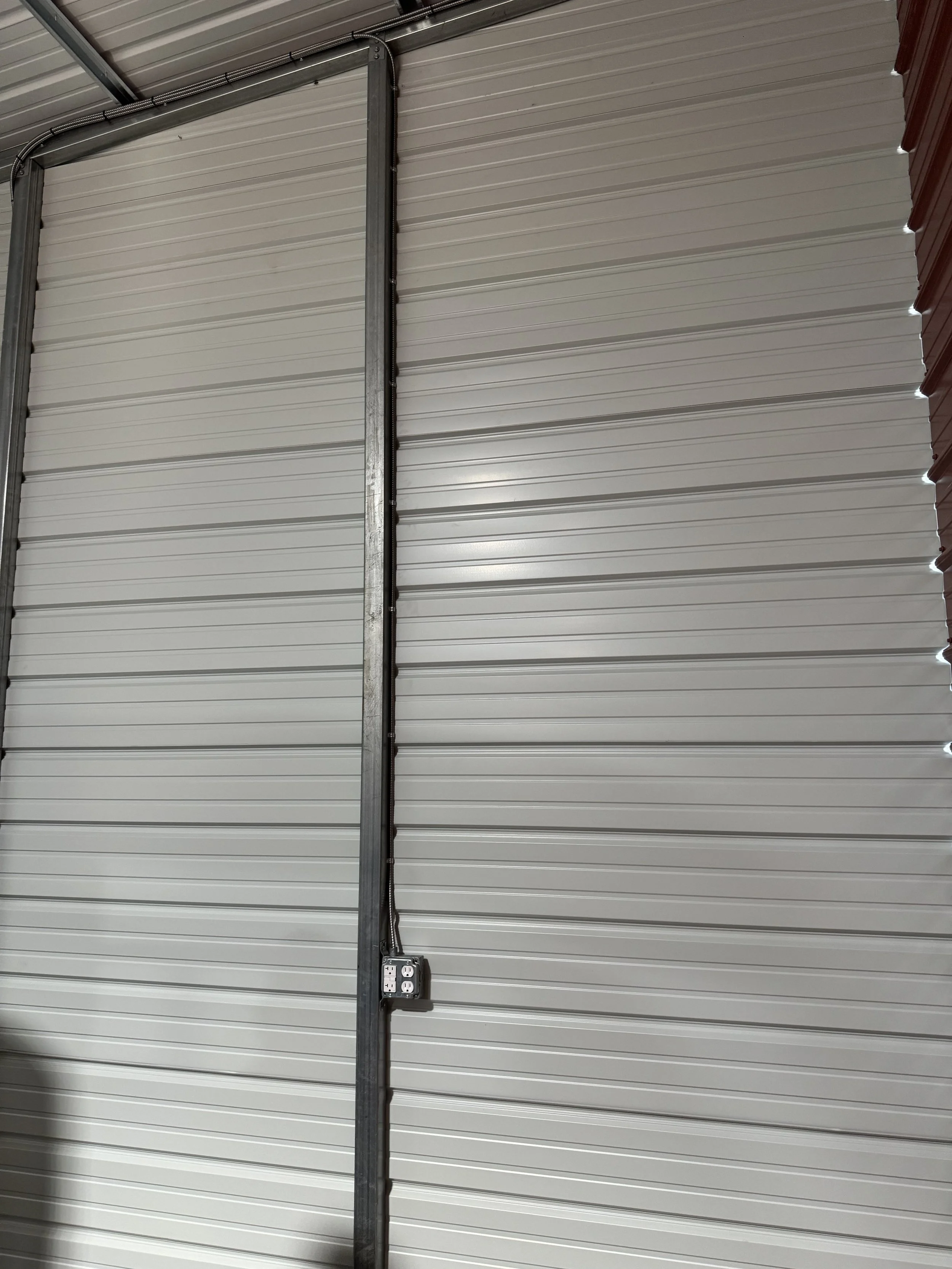 Close-up of a garage door with metal framing and electrical outlet.