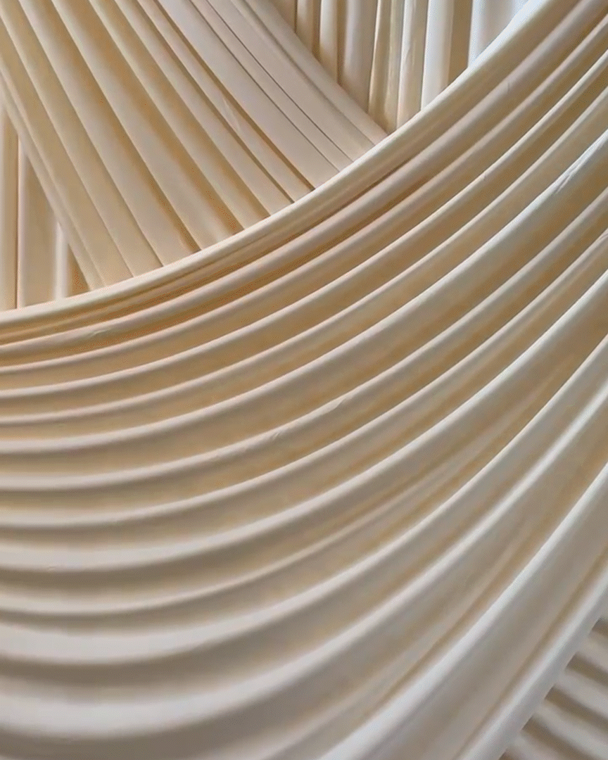 Close-up of beige fabric draped and layered to create folds and waves.