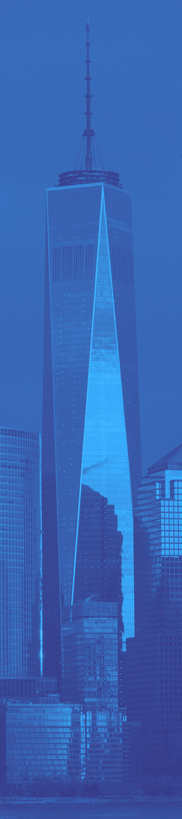 A skyscraper with a tall antenna on top, reflecting the blue sky and surrounding buildings.