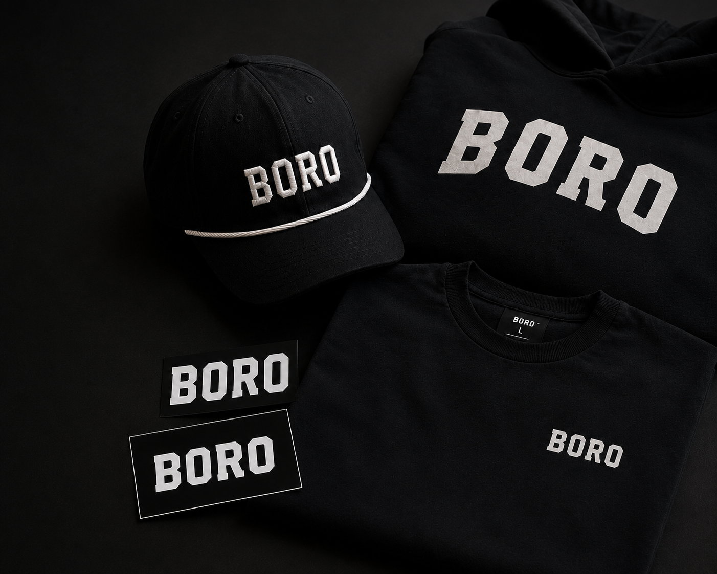 Black clothing and accessories with the word 'BORO' in white lettering, including a cap, a hoodie, a t-shirt, and two stickers.