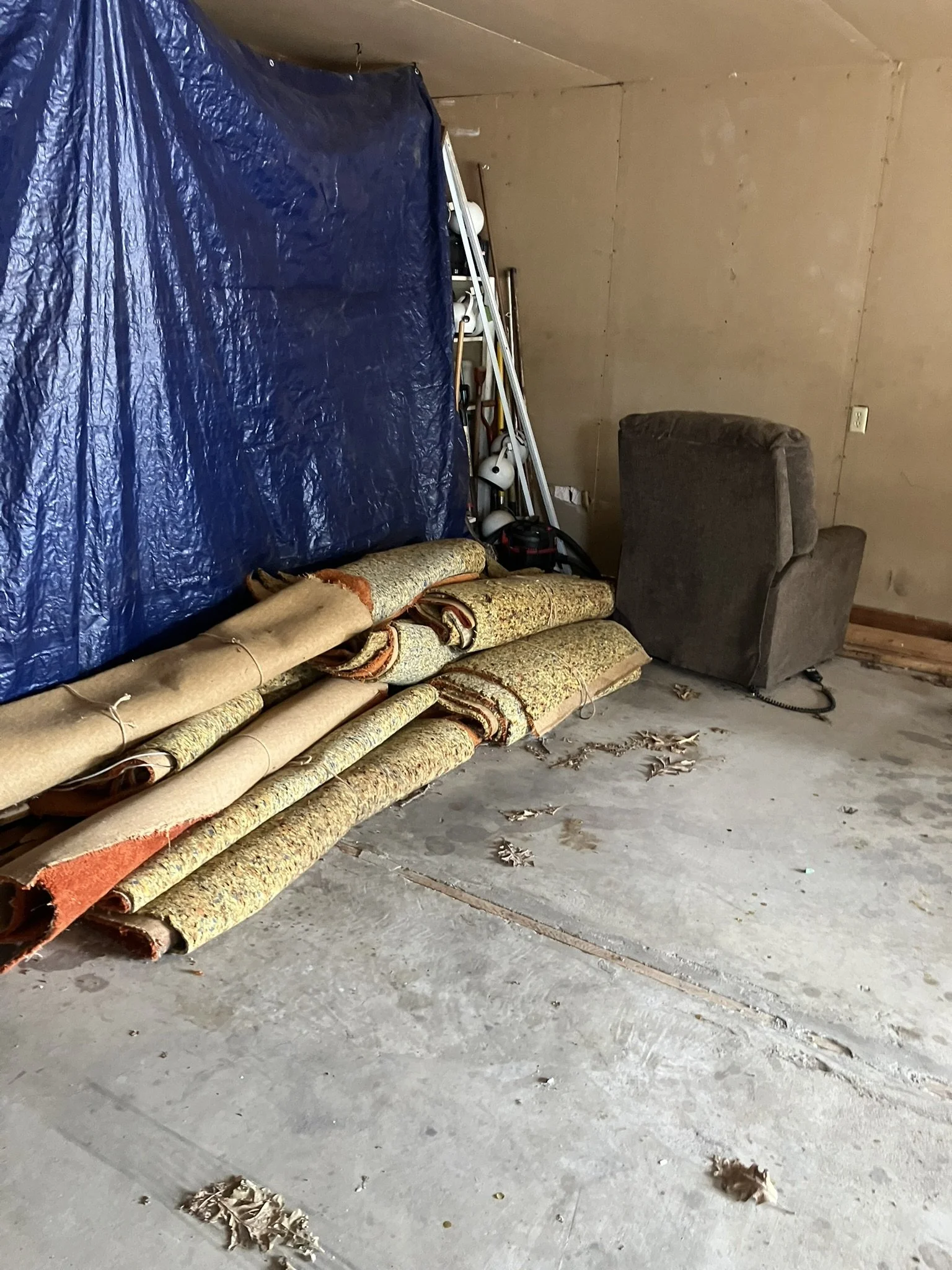 Garage cluttered with rolled up carpet, furniture, and other unwanted items before a complete junk removal and cleanout by Junk Boys.