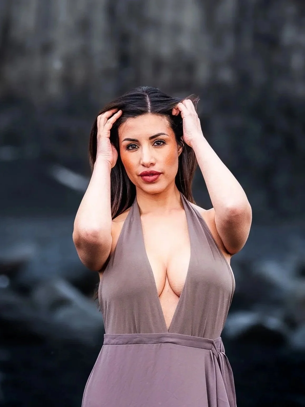 Michelle Benitez, Univision news anchor, posing on a black sand beach in Iceland with a blurred natural background.