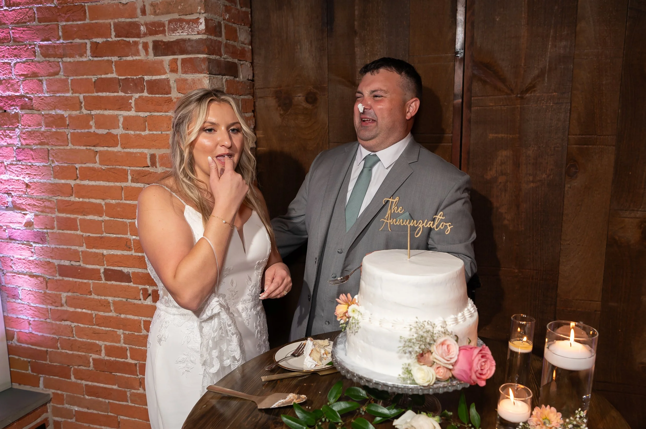 Bride and groom cutting their wedding cake at The Booking House, Manheim PA, brick wall in the background.
