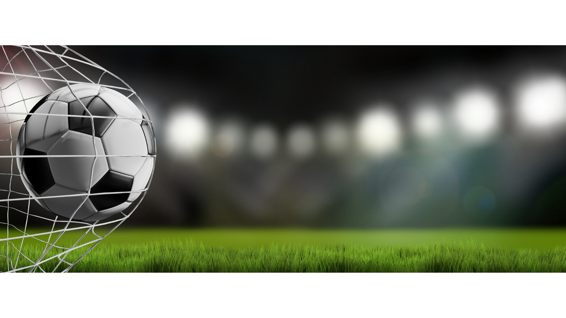 Soccer ball hitting the back of a net on a green field at night