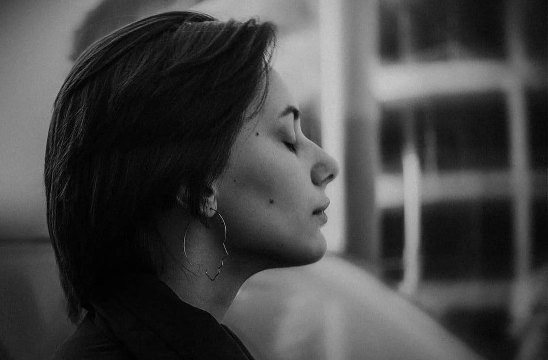 Side profile of a woman with short hair, eyes closed, in black and white portrait.